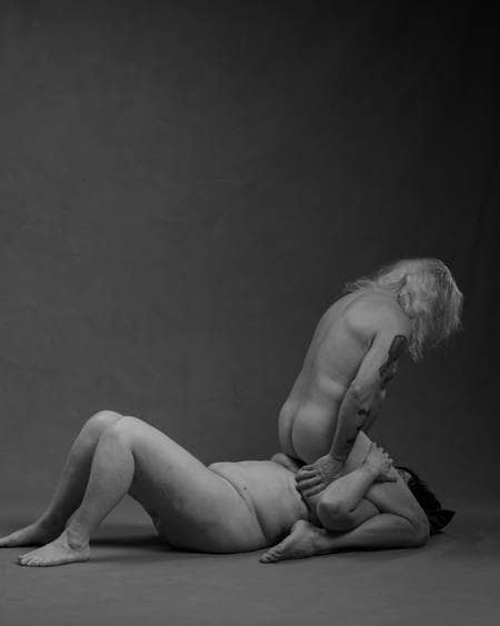En eldre mann med langt hvitt hår kneler over en kvinne med mørkt hår som ligger på ryggen. Han sitter over ansiktet hennes med beina spredt. De simulerer oralsex. Begge er nakne, men kjønnsorganene er ikke synlige. De er et godt voksent par.