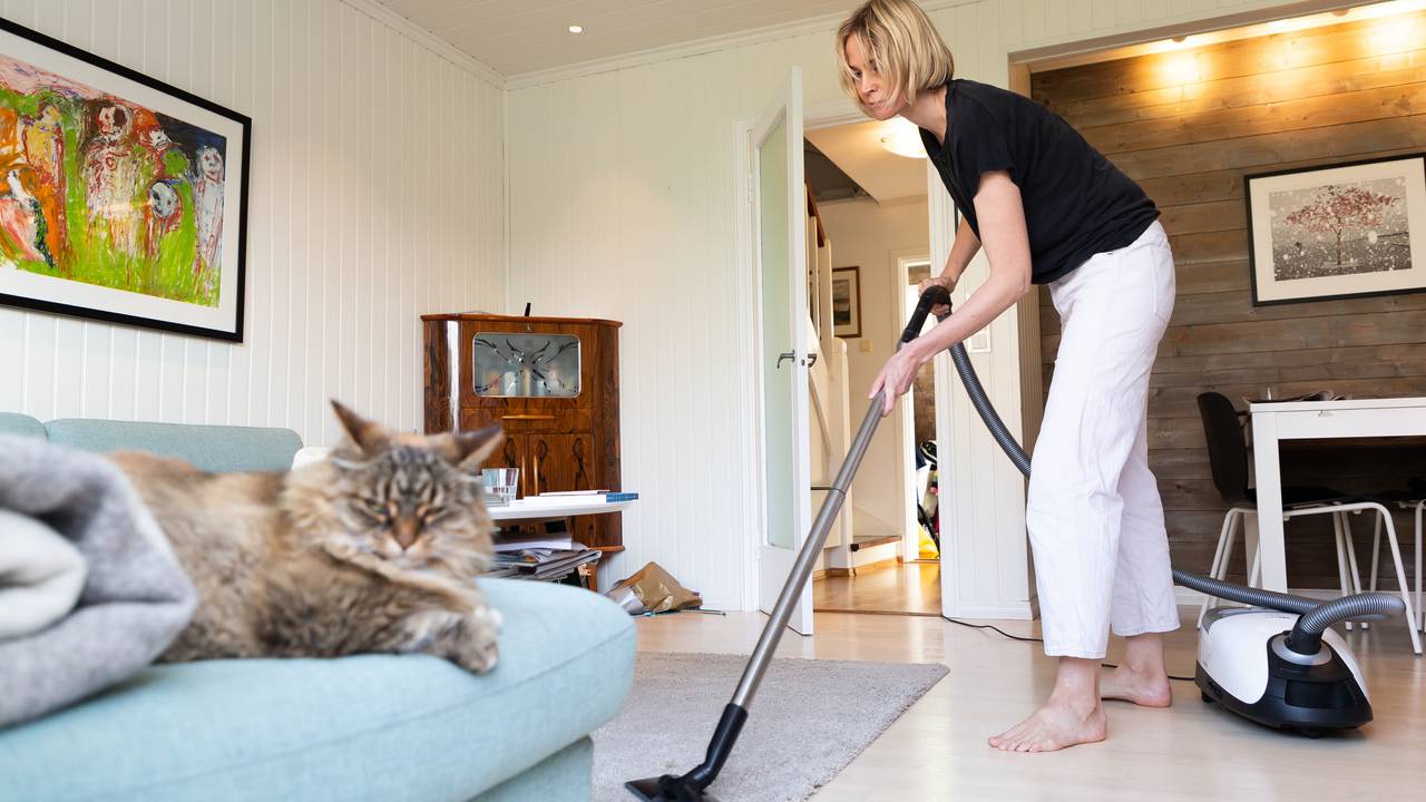 Sandra Lillebø støvsuger med katten i forgrunnen