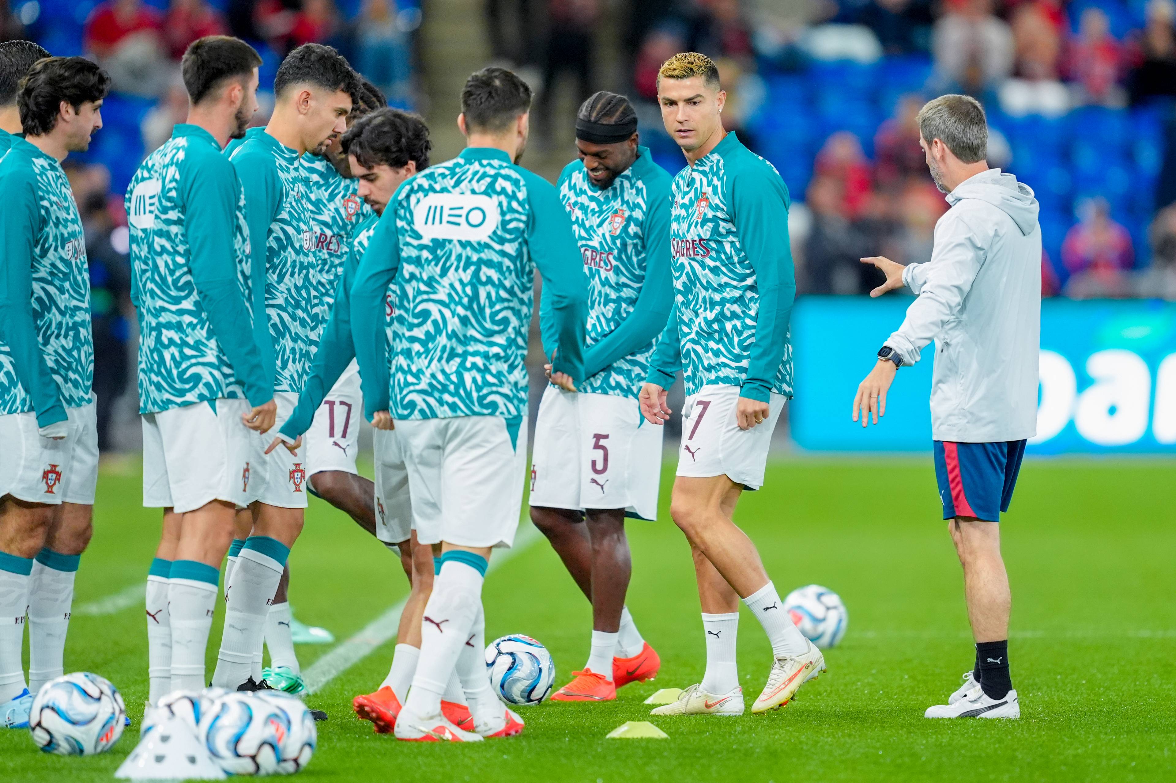Cristiano Ronaldo og det portugisiske landslaget trener på fotballbane sammen med en trener. (Bildebeskrivelsen er laget av en KI-tjeneste)