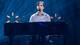 Foto: Thomas Andersen / TV 2 En mann i lysblå skjorte sitter ved et piano og synger, han sitter på scenen og har en lang mikrofon foran seg som stikker opp bak pianoet. Bak ham er lys i stjerneformasjoner.