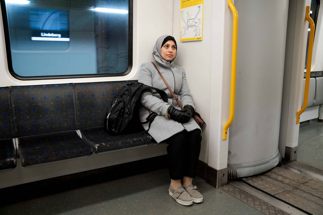 Mona sitter alene og lener seg mot veggen på T-banen. Det er ingen passasjerer ved siden av henne.