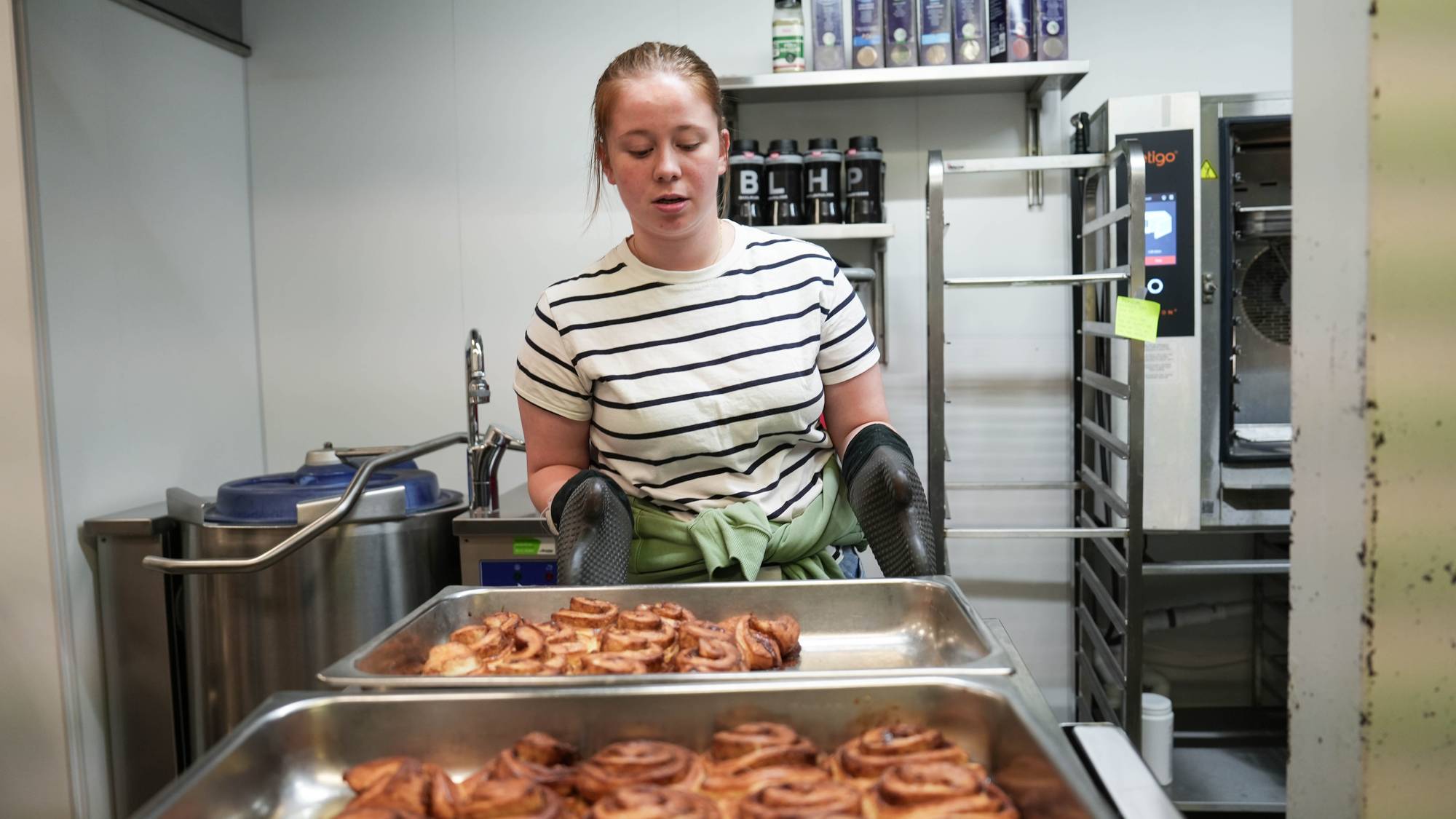 To unge kvinner som baker boller og koser seg på folkehøgskole.