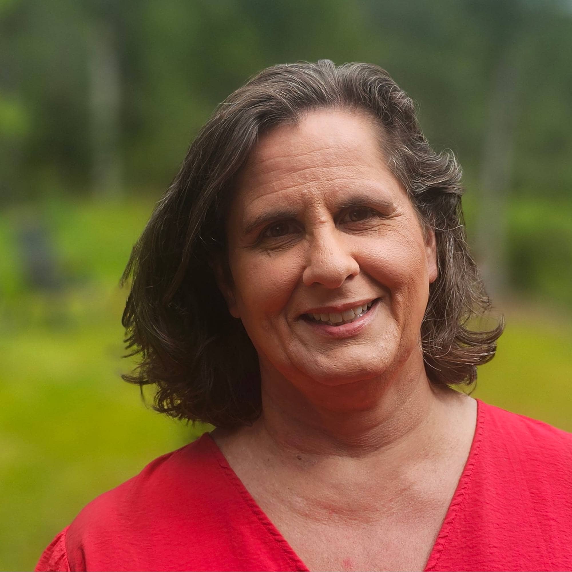 en smilende dame i rødt, det er skog i bakgrunn