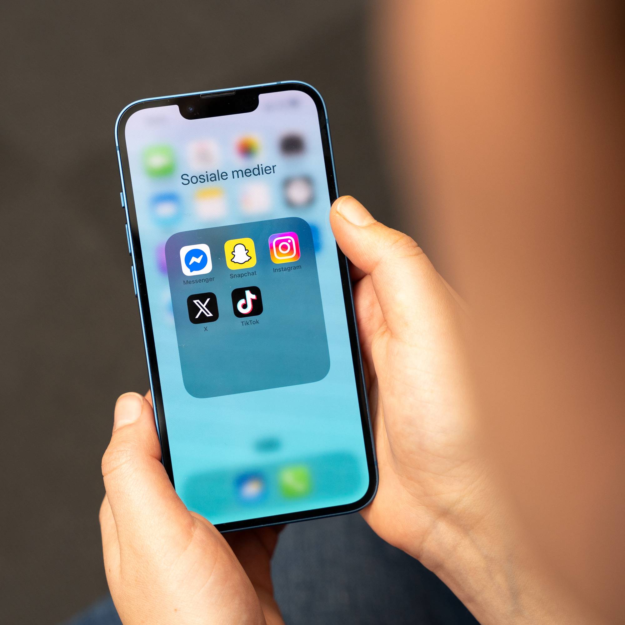 Illustrasjonsbilde av sosiale medier. Bildet viser noen som holder en mobil. På skjermen er det bilde av flere sosiale medier-plattformer. 