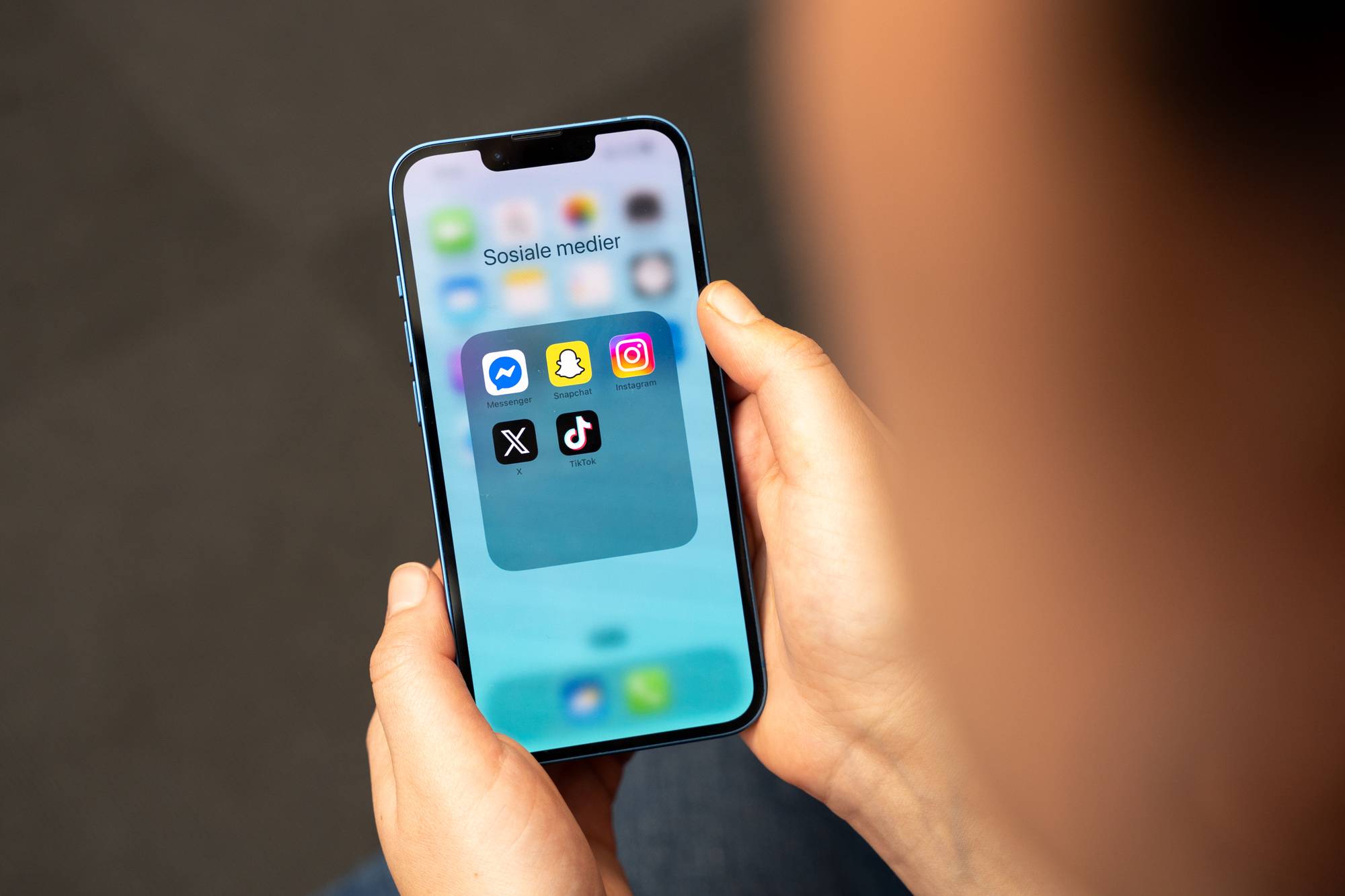 Illustrasjonsbilde av sosiale medier. Bildet viser noen som holder en mobil. På skjermen er det bilde av flere sosiale medier-plattformer. 