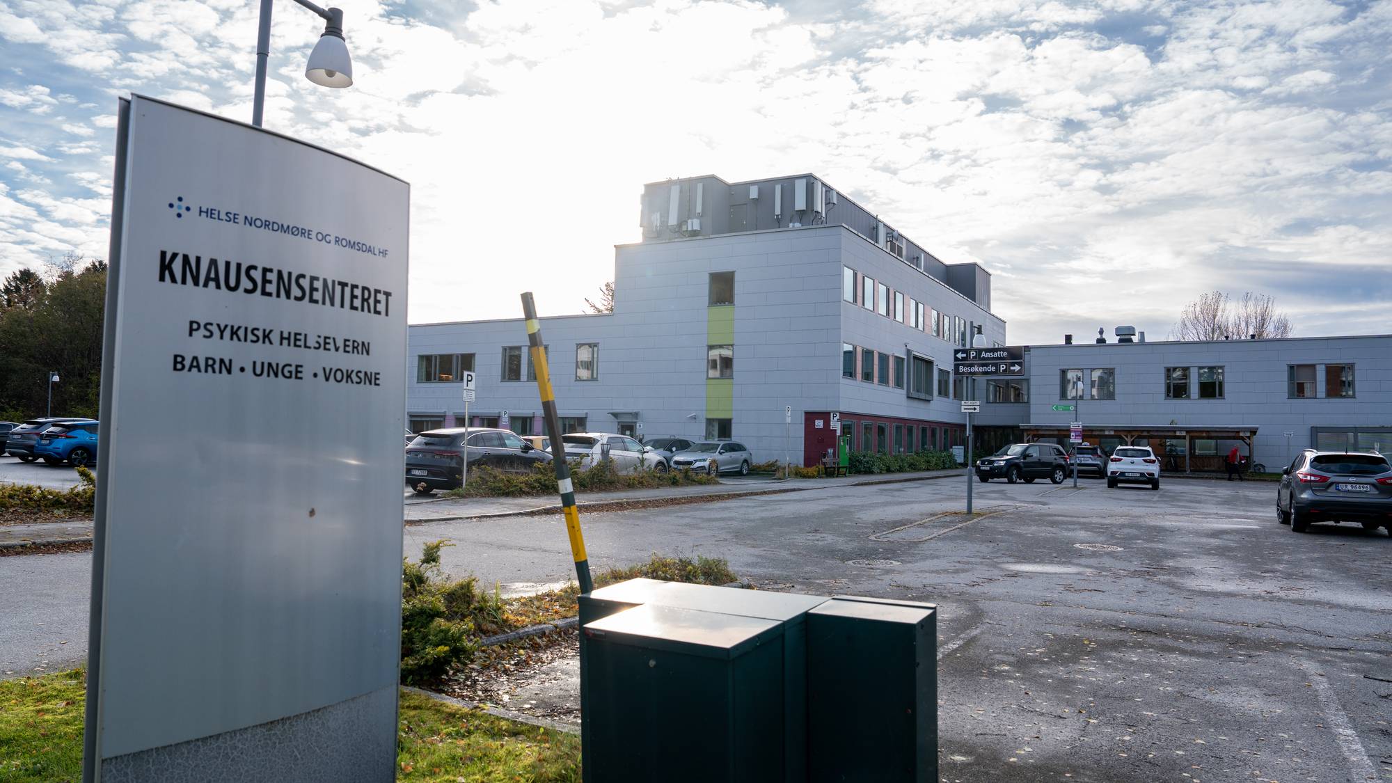 Skilt ved Knausensenteret med parkeringsplass og sykehusbygg i bakgrunnen. (Bildebeskrivelsen er laget av en KI-tjeneste)