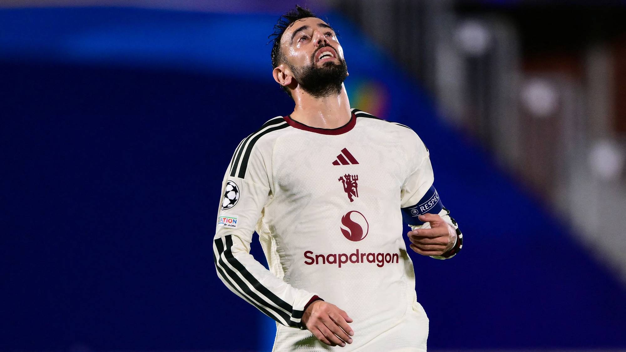 Bruno Fernandes i Manchester United-drakt ser oppover med et oppgitt uttrykk på en fotballstadion. (Bildebeskrivelsen er laget av en KI-tjeneste)