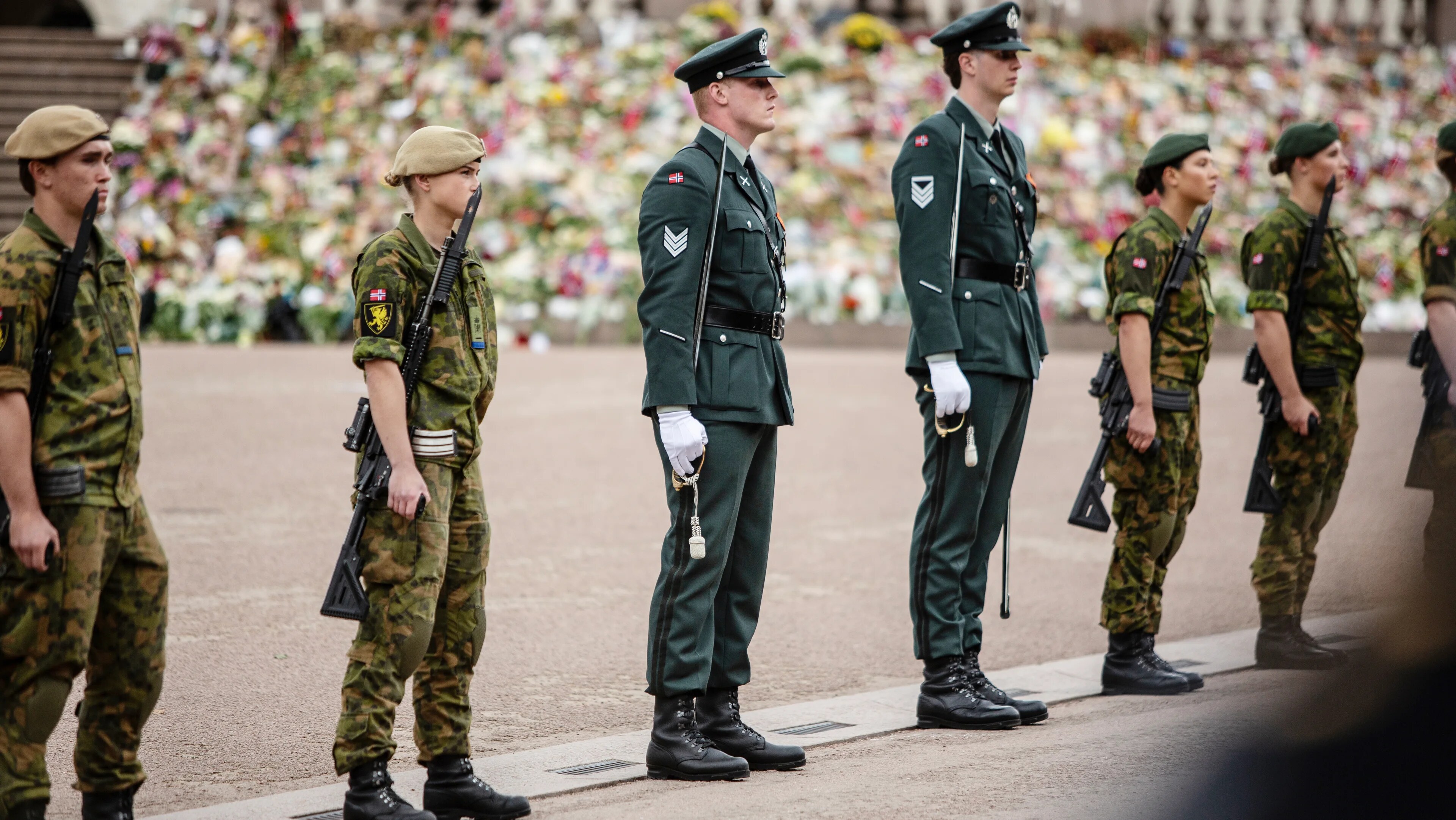 Gardister står oppstilt foran et blomsterhav ved Oslo domkirke. (Bildebeskrivelsen er laget av en KI-tjeneste)