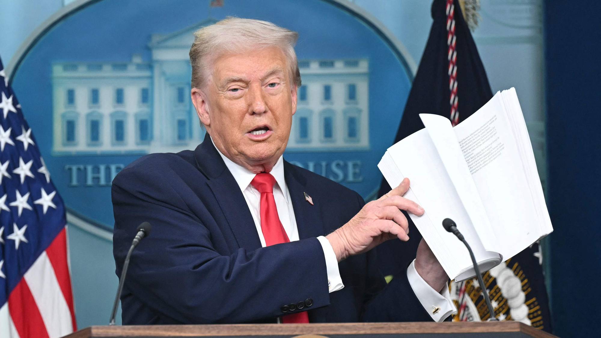 Donald Trump holder opp en hvit mappe.