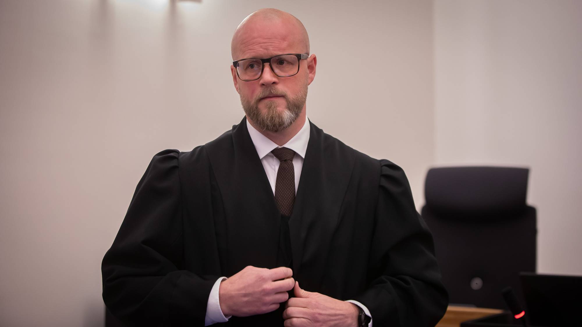 Forsvarer Erlend Hjulstad Nilsen i Frosta-saken. Han er i rettssalen og han er i ferd med å knappe igjen kappen. Han kikker betenkt til sin høyre side