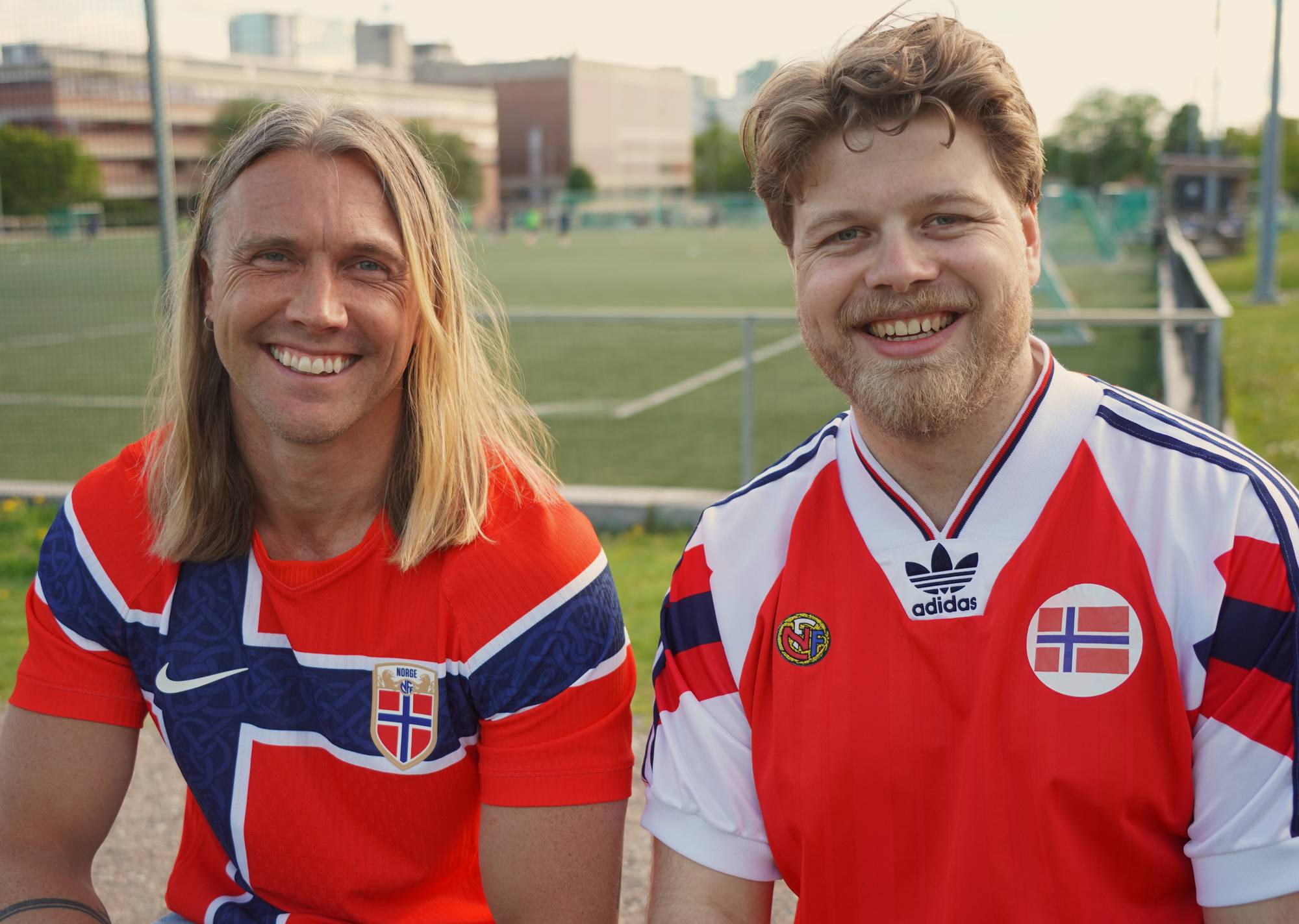 To menn i norske fotballtrøyer smiler mot kamera