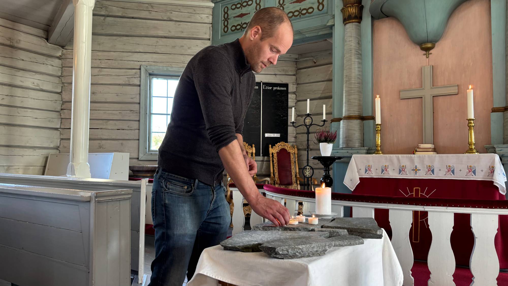 En mann tenner lys på et alter i en trekirke. (Bildebeskrivelsen er laget av en KI-tjeneste)