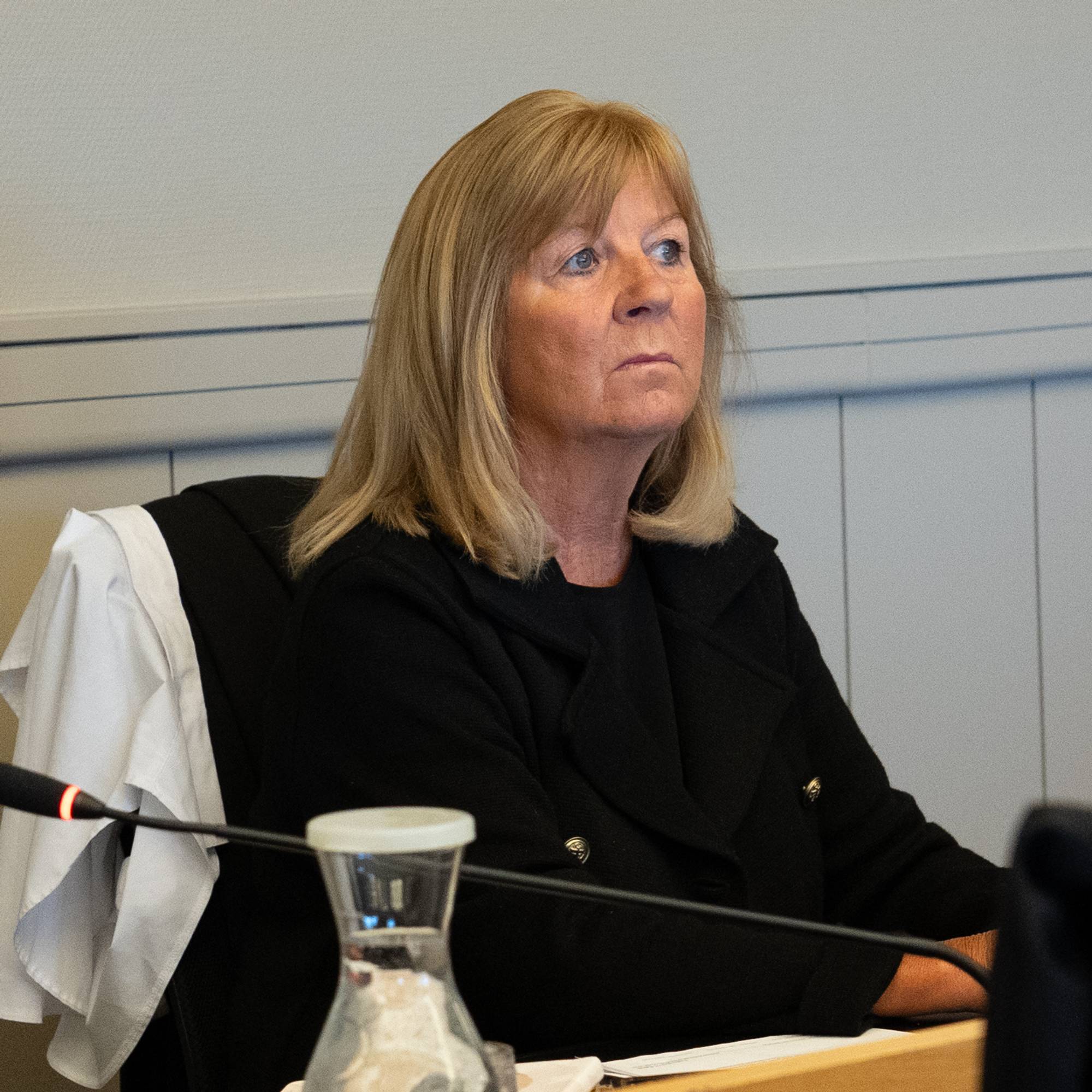 En kvinne sitter ved et bord i en rettssal.