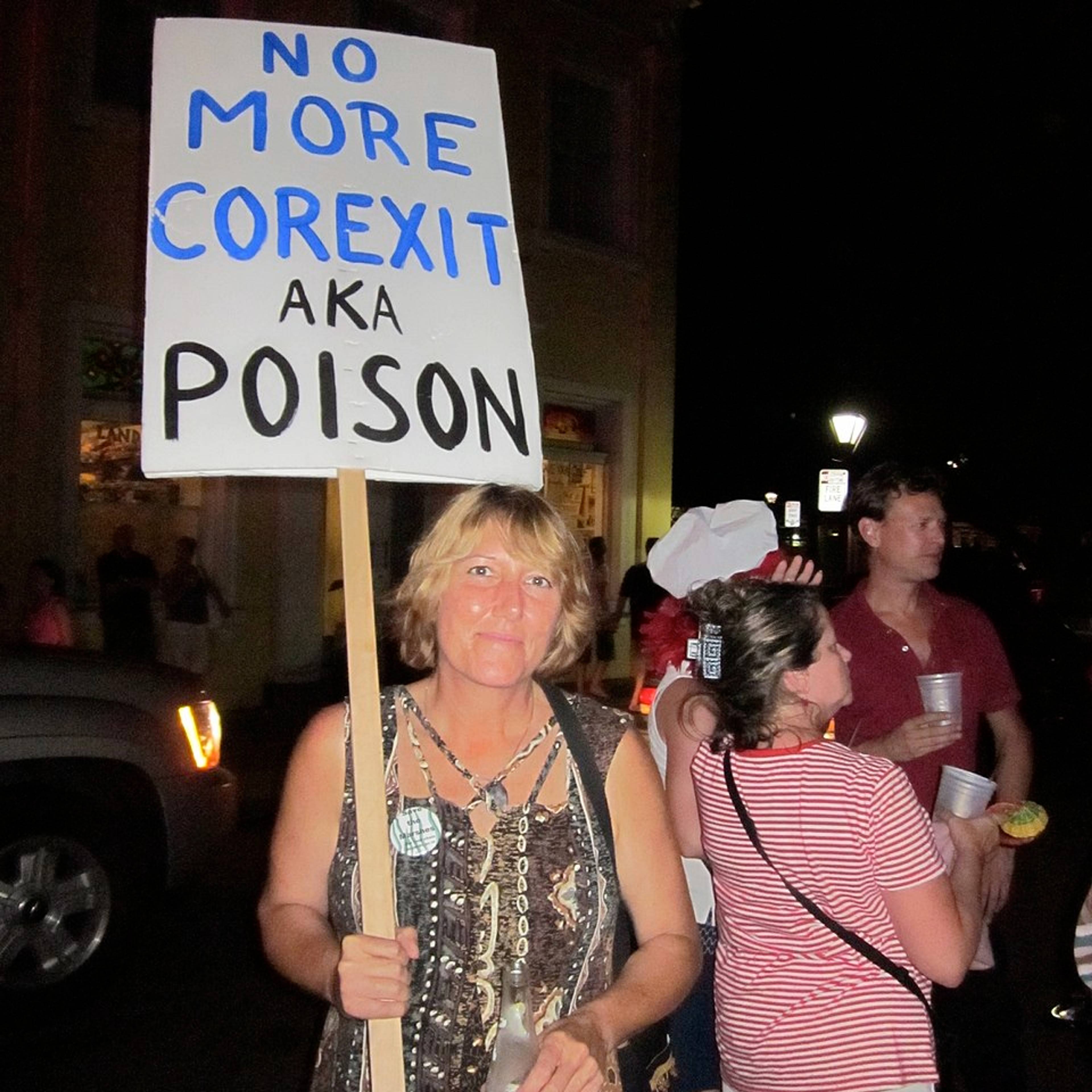 En demonstrant holder opp en plakat hvor det står: Ikke mer Corexit  også kjent som gift.