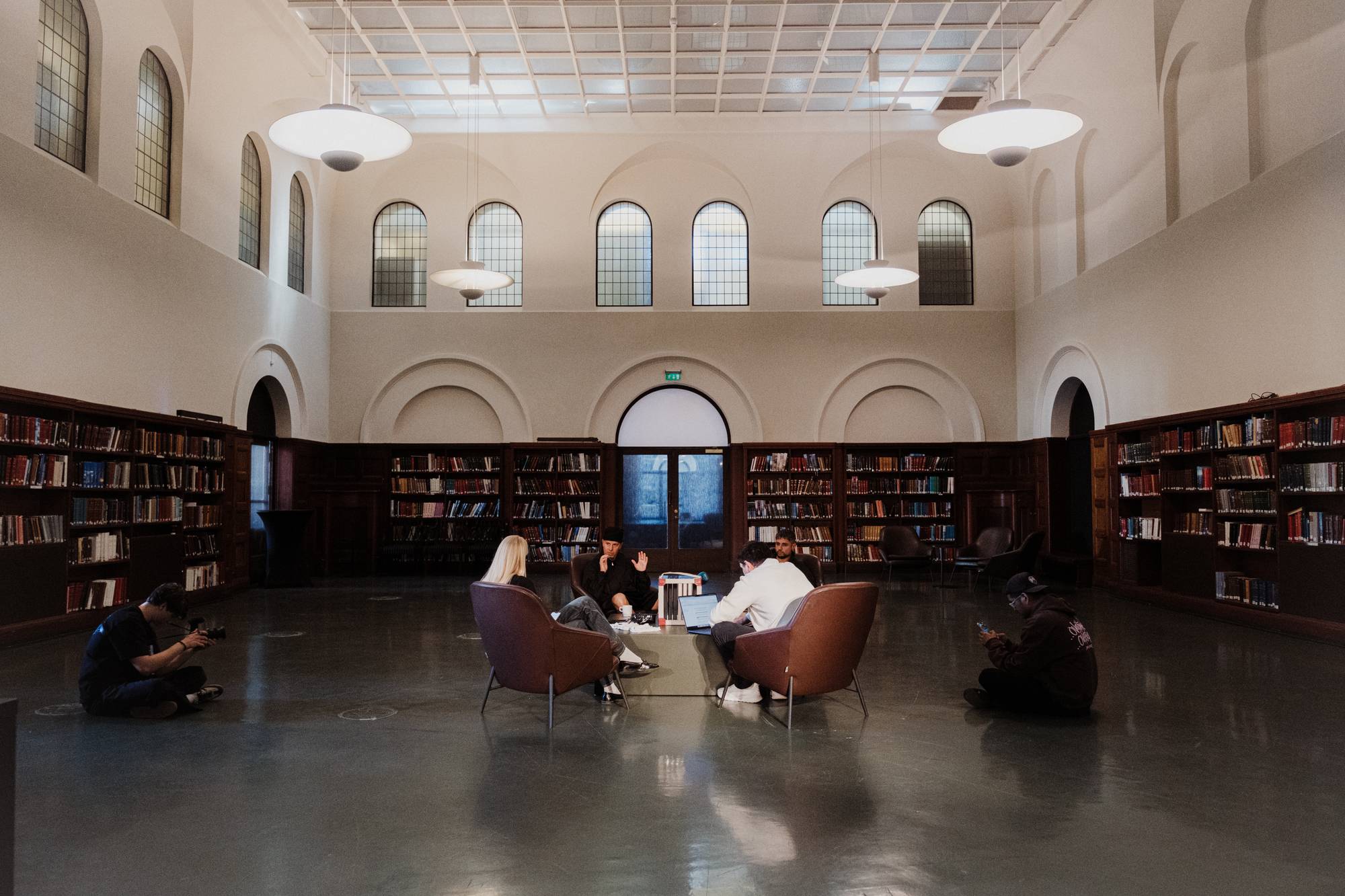 Et stort rom på et bibliotek. I midten av rommet sitter fire personer