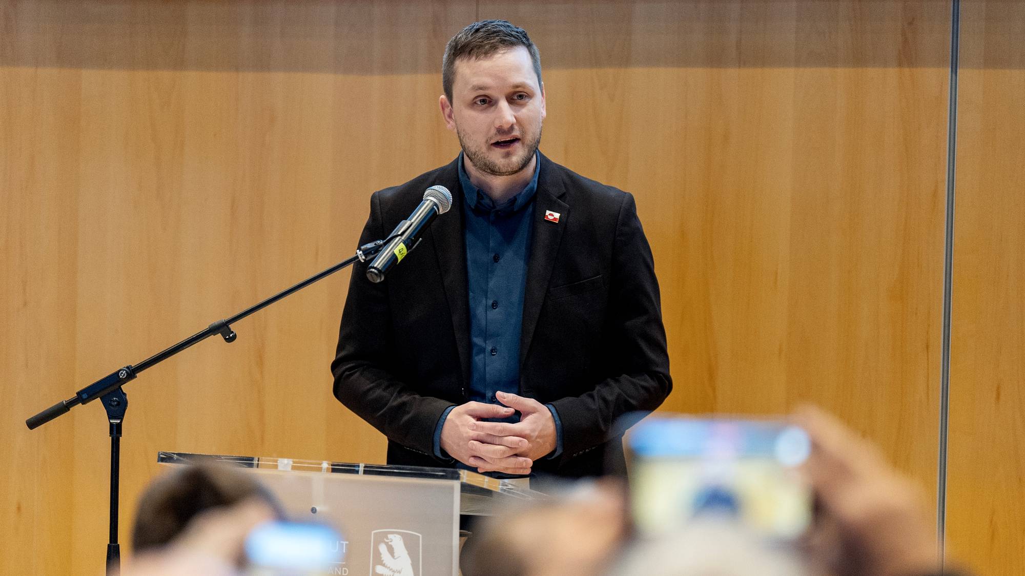 Grønlands statsminister og Danmarks statsminister går ute på gaten sammen, med en stor mengde journalister rundt dem. 