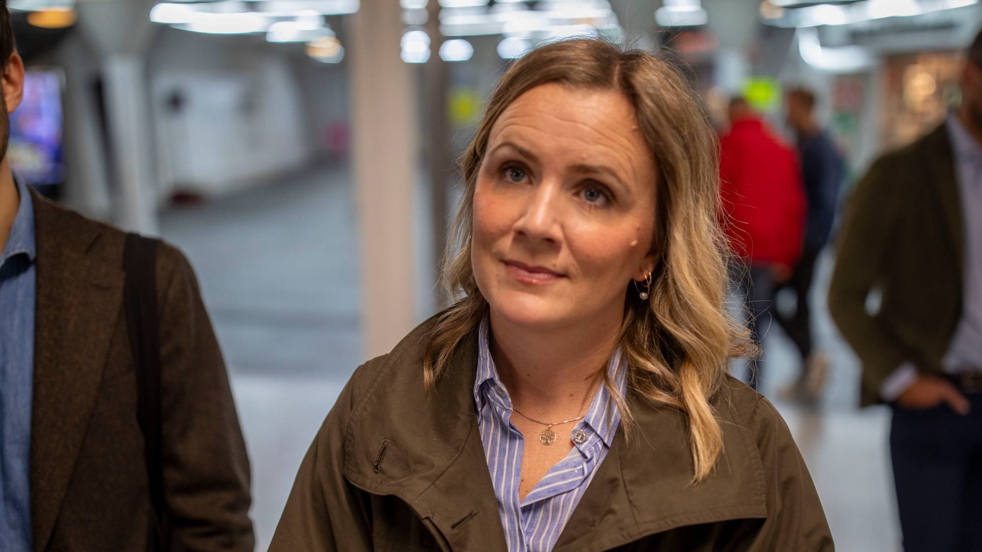 Marit Vea står innendørs omgitt av personer i en gang. (Bildebeskrivelsen er laget av en KI-tjeneste)