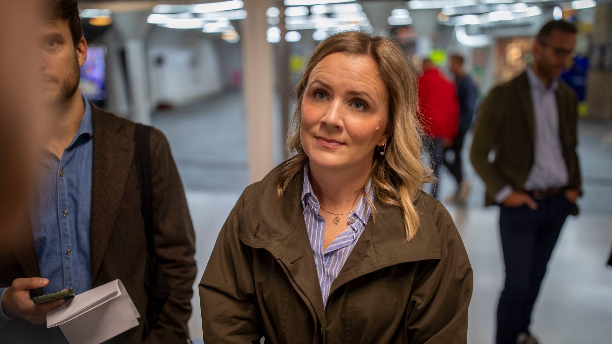 Marit Vea står innendørs omgitt av personer i en gang. (Bildebeskrivelsen er laget av en KI-tjeneste)