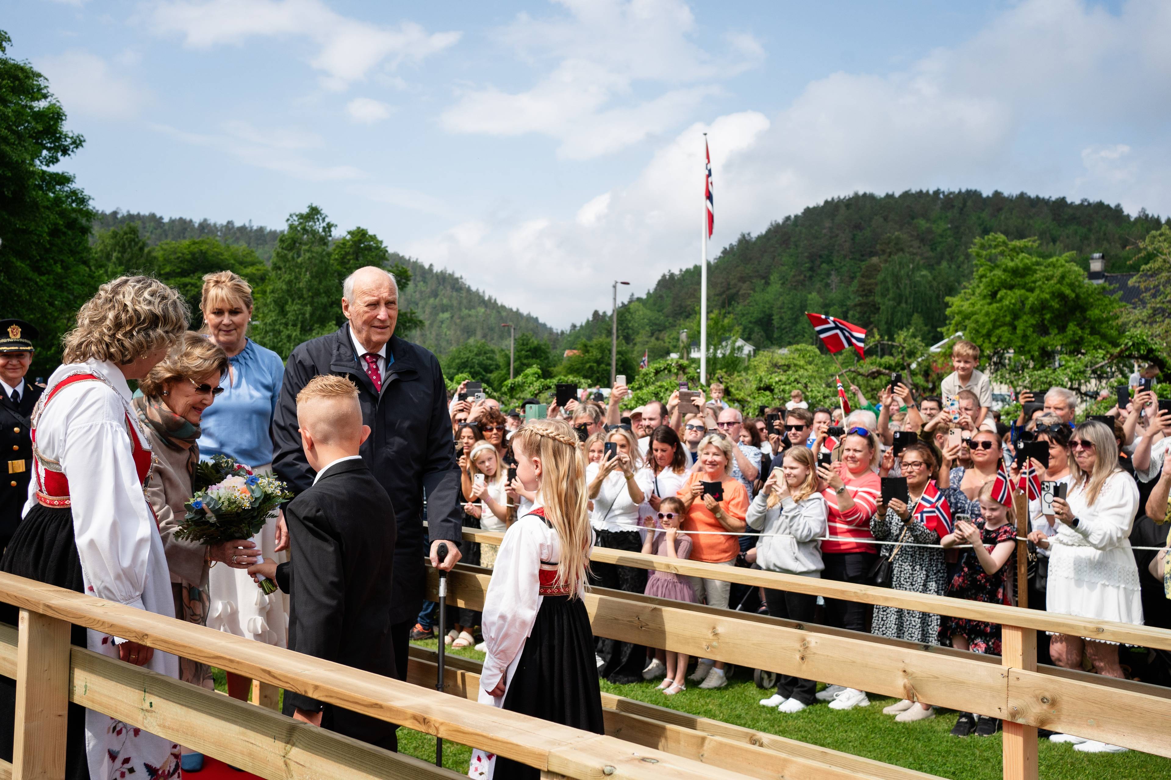 Kong Harald og dronning Sonja tas imot av blomsterbarn når de ankommer Froland kommune