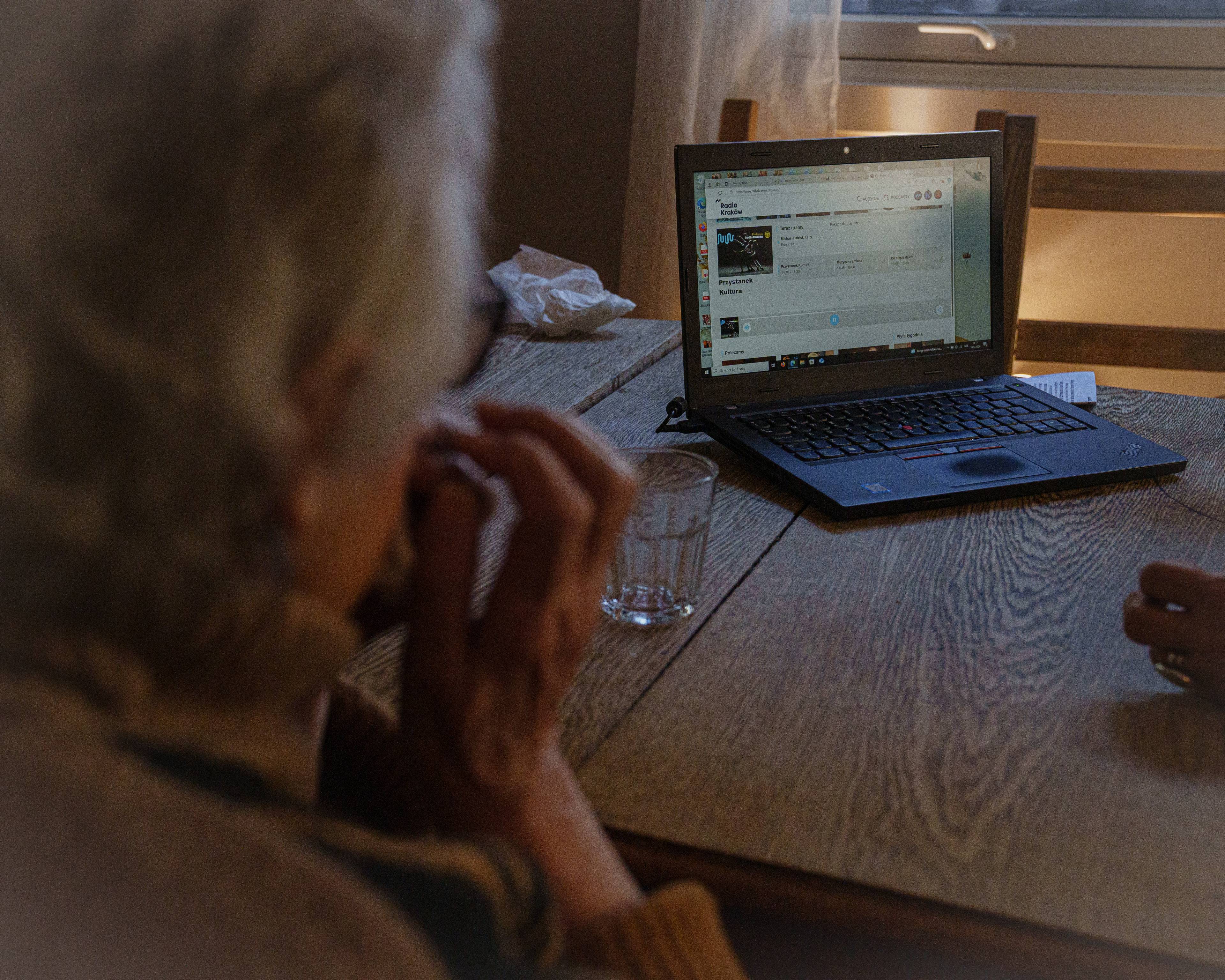 Magdalena sitter ved et bord og ser mot en laptop med Radio Krakow påskrudd