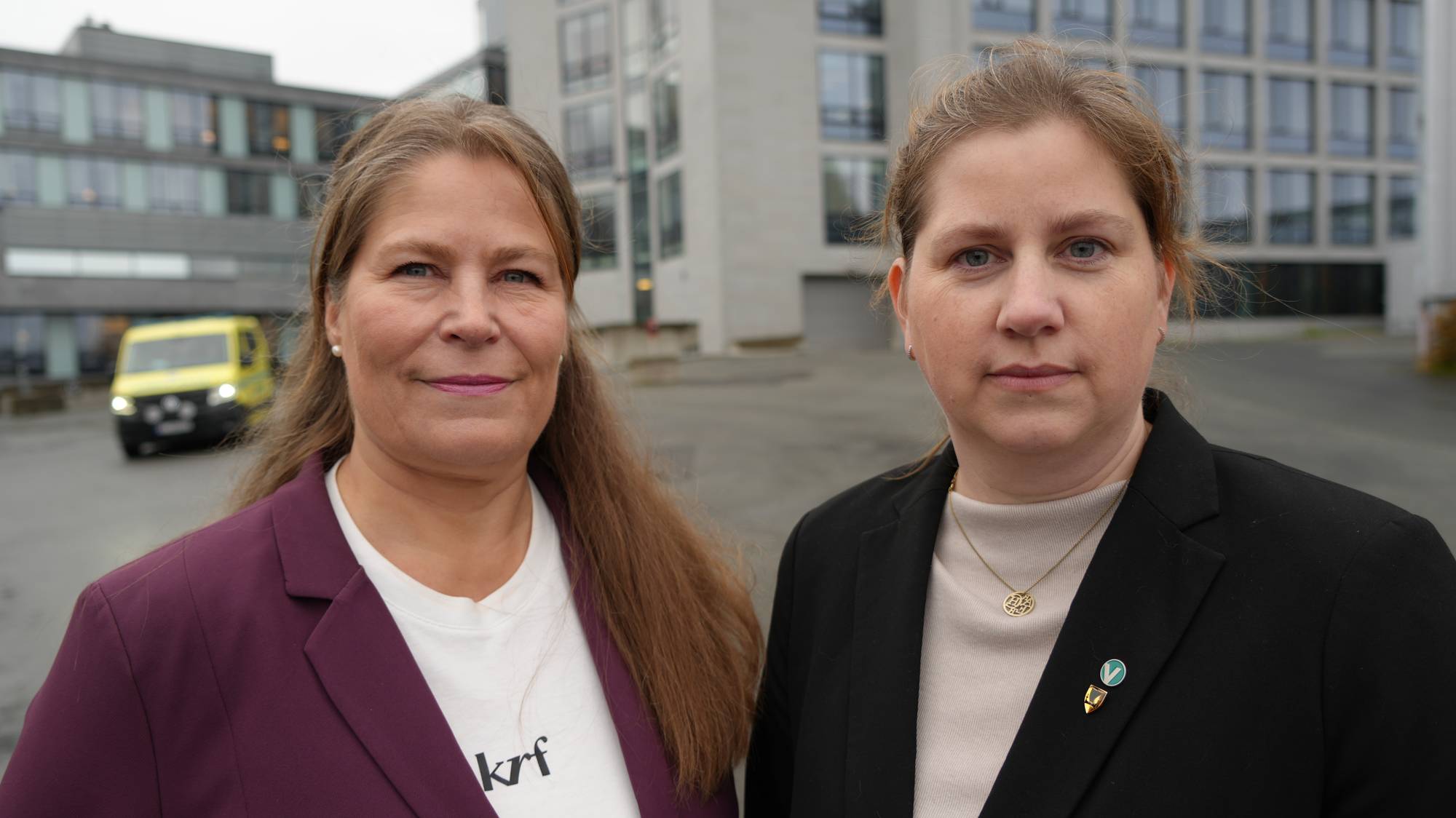 To kvinner foran en kontorbygning. En ambulanse er synlig i bakgrunnen. (Bildebeskrivelsen er laget av en KI-tjeneste)