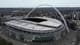 Frank Augstein / AP / NTB Wembley stadion vises fra luften, med det karakteristiske buen i taket. Omgivelsene inkluderer moderne bygninger og tomteområder. Parkeringsplasser er synlige rundt stadion, som ser ut til å være forberedt for et arrangement. Bildet er tatt på en overskyet dag.