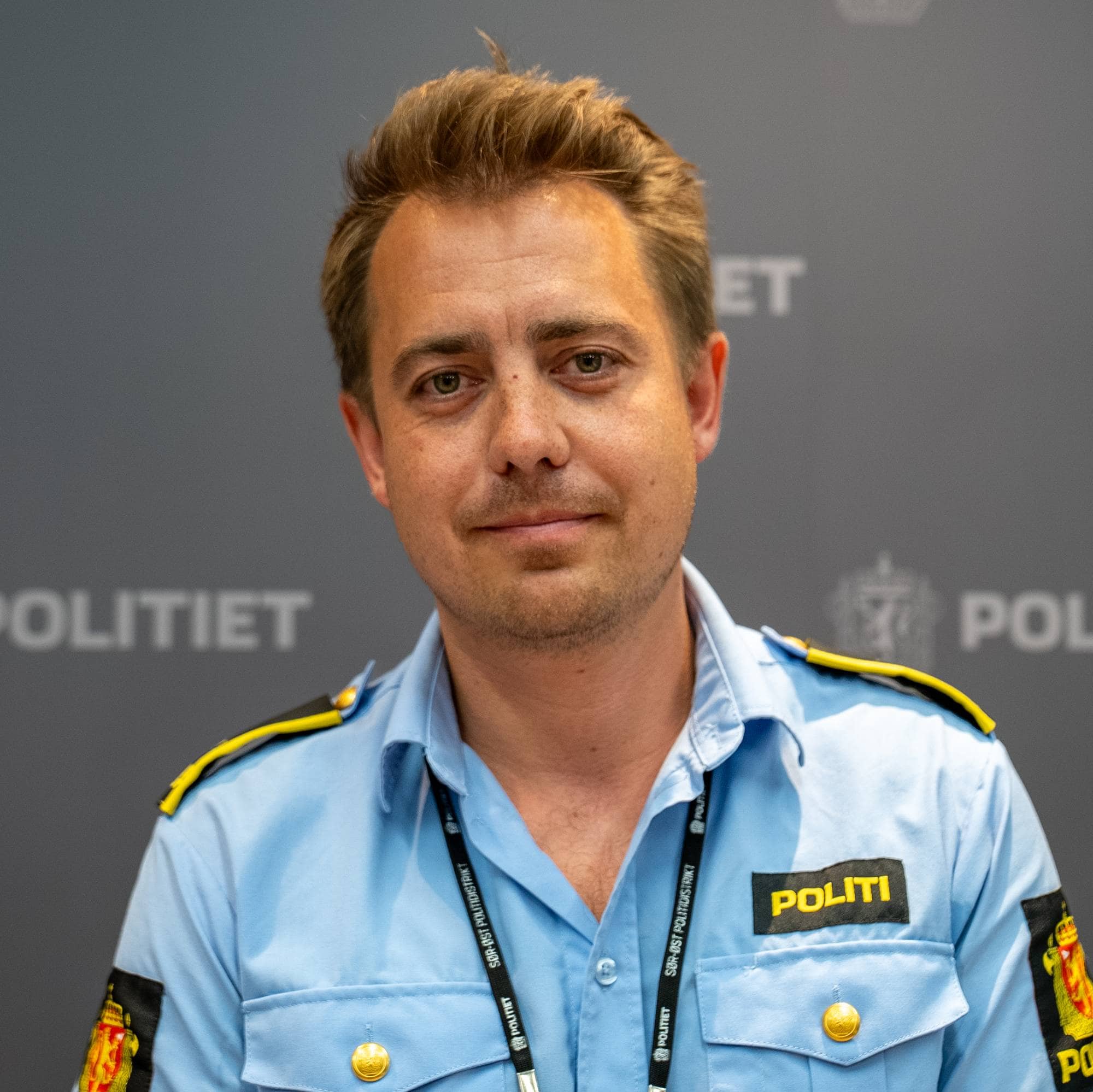 En mann med brunt, korthår og politiuniform
