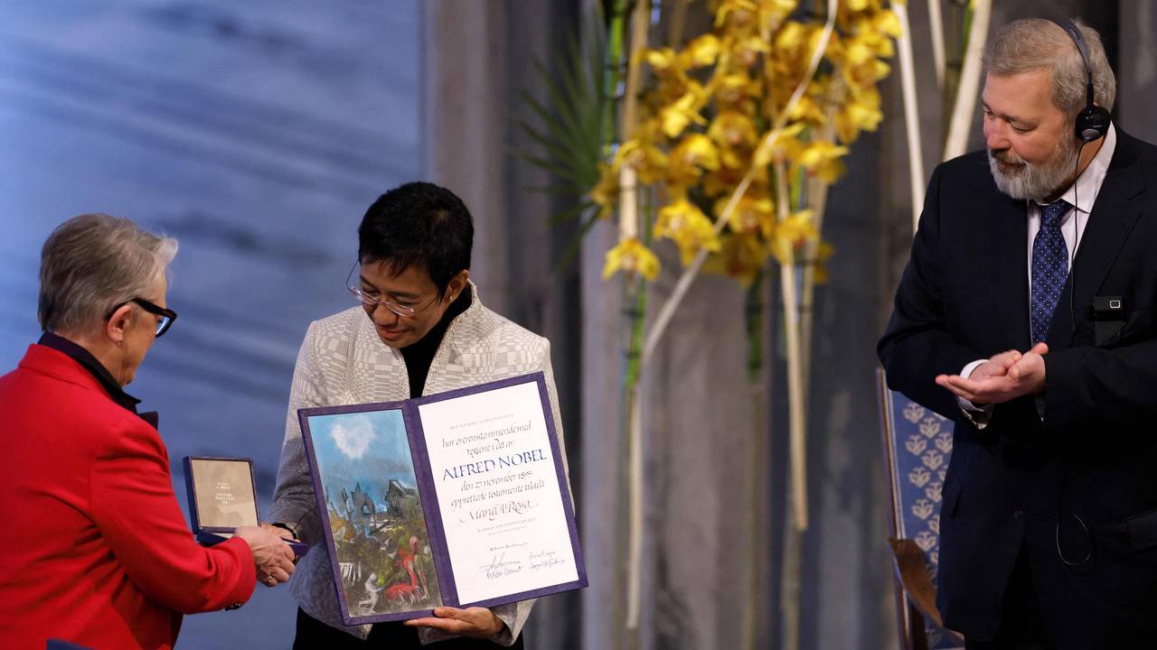 Leder av Nobelkomiteen Berit Reiss-Andersen overrekker gullmedalje og diplom til Maria Ressa, mens medvinner Dmitrij Muratov applauderer.