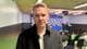 Lars Bryne / NRK En mann med blondt hår i en mørk jakke står foran et publikum. Bak ham er det et bord dekket med en blå duk og en logo-vegg. Det er flere tomme stoler i rommet. Bakgrunnen er en konferansesal. (Bildebeskrivelsen er laget av en KI-tjeneste)