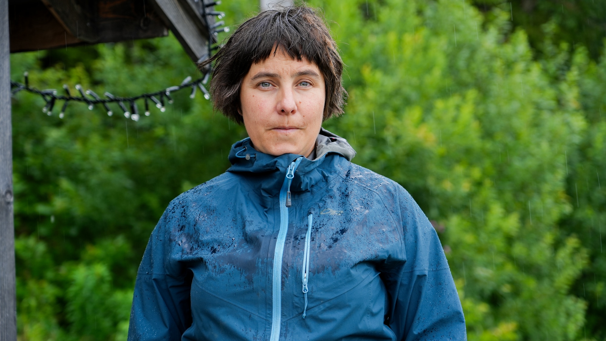 Bilde av en kvinne i blå regnjakke som ser inn i kamera