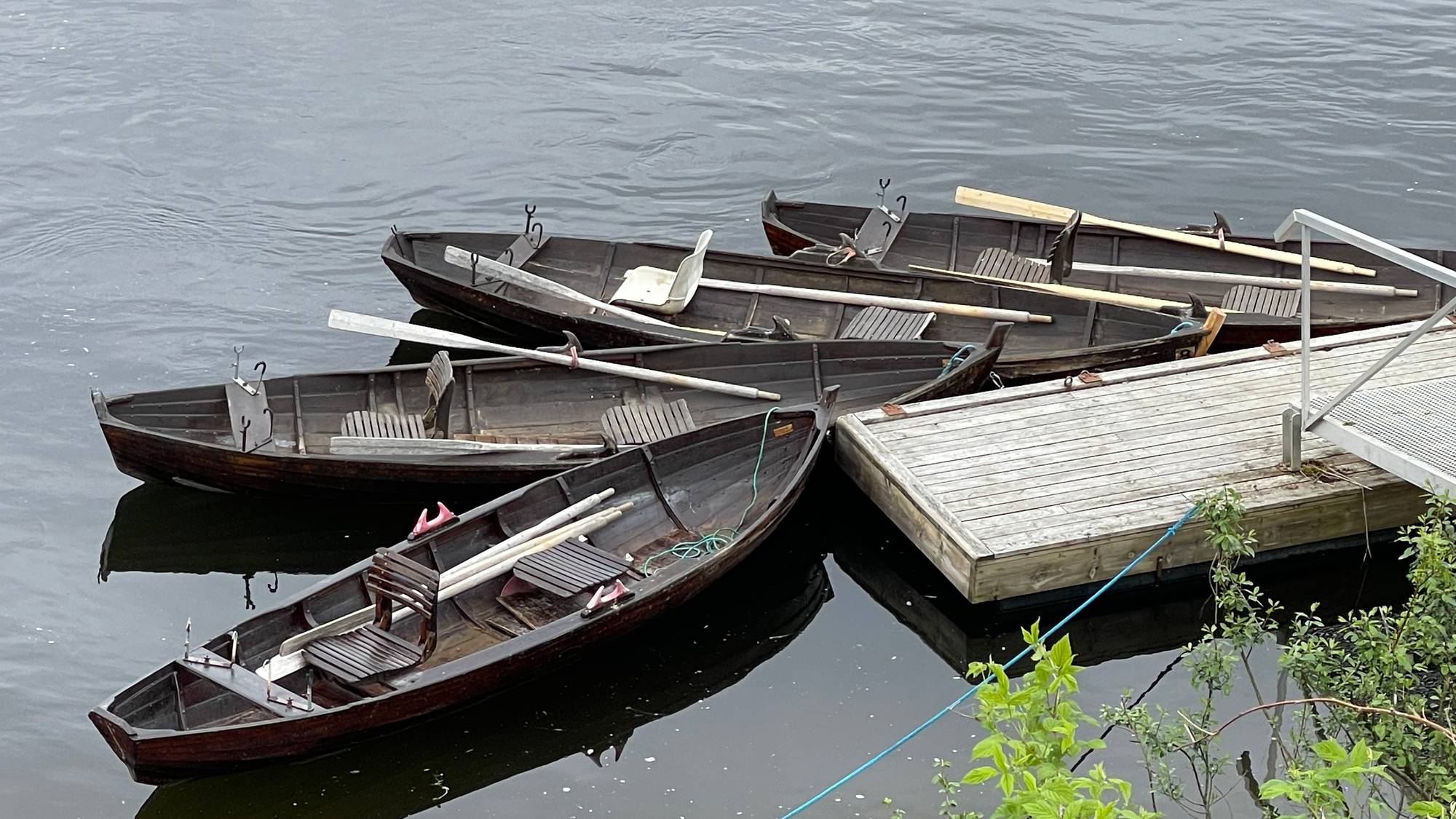 Fire båter ligger ved en flytebrygge i elva Namsen i Trøndelag, klar til å bli brukt til laksefiske. 