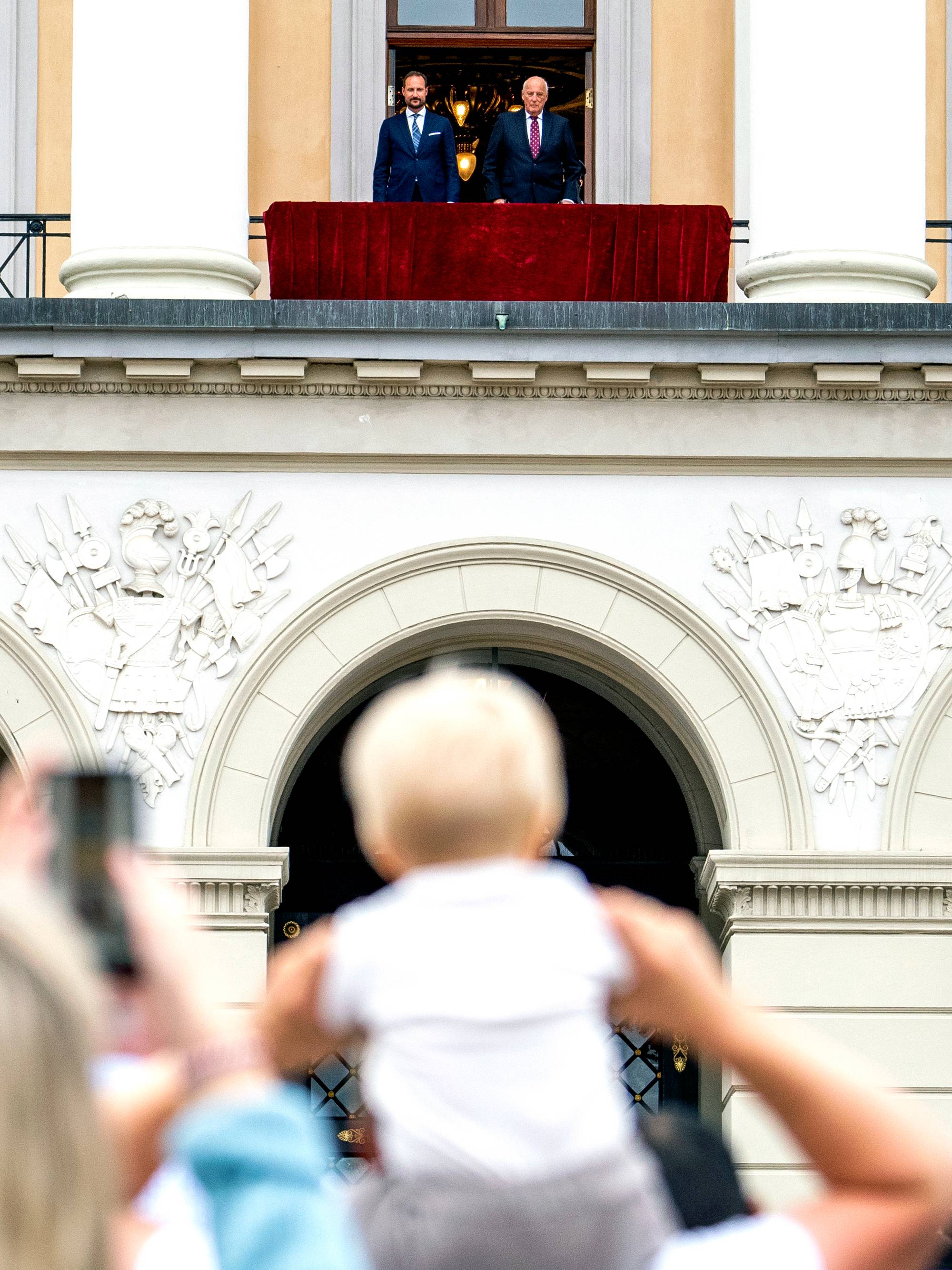 Kong Harald og kronprins Haakon står ved siden av hverandre på Slottsbalkongen