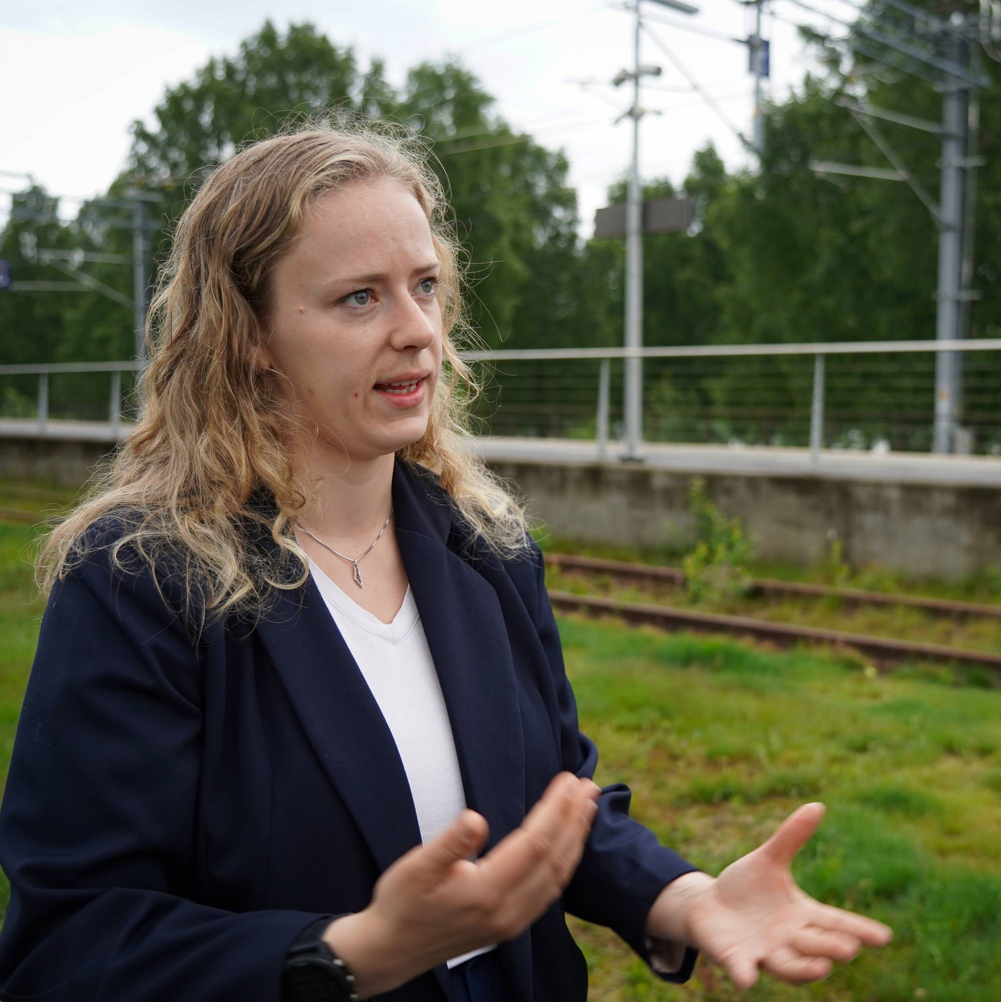 SV-politiker Tuva Todnem Lund gestikulerer med hendene ved jernbane-stasjon 