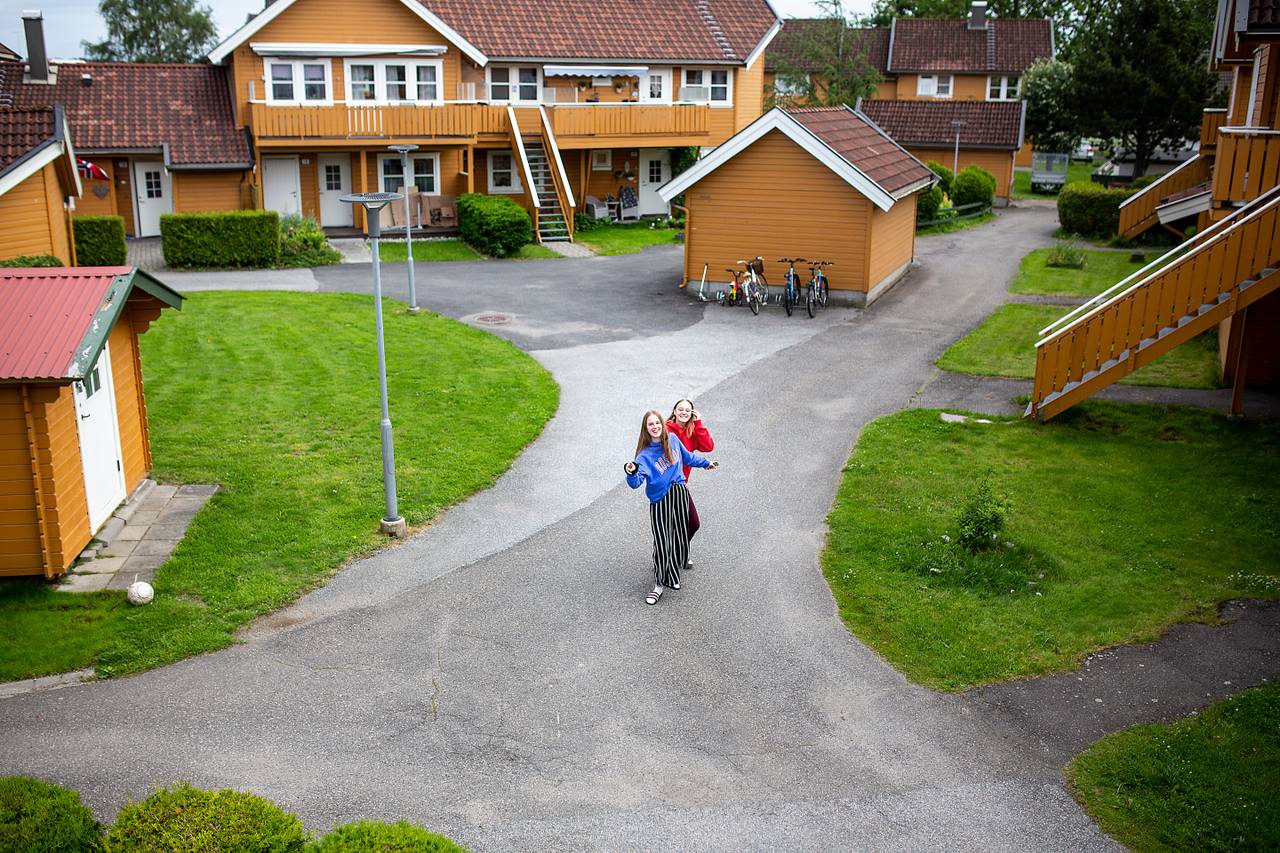 To jenter står blant gule hus.