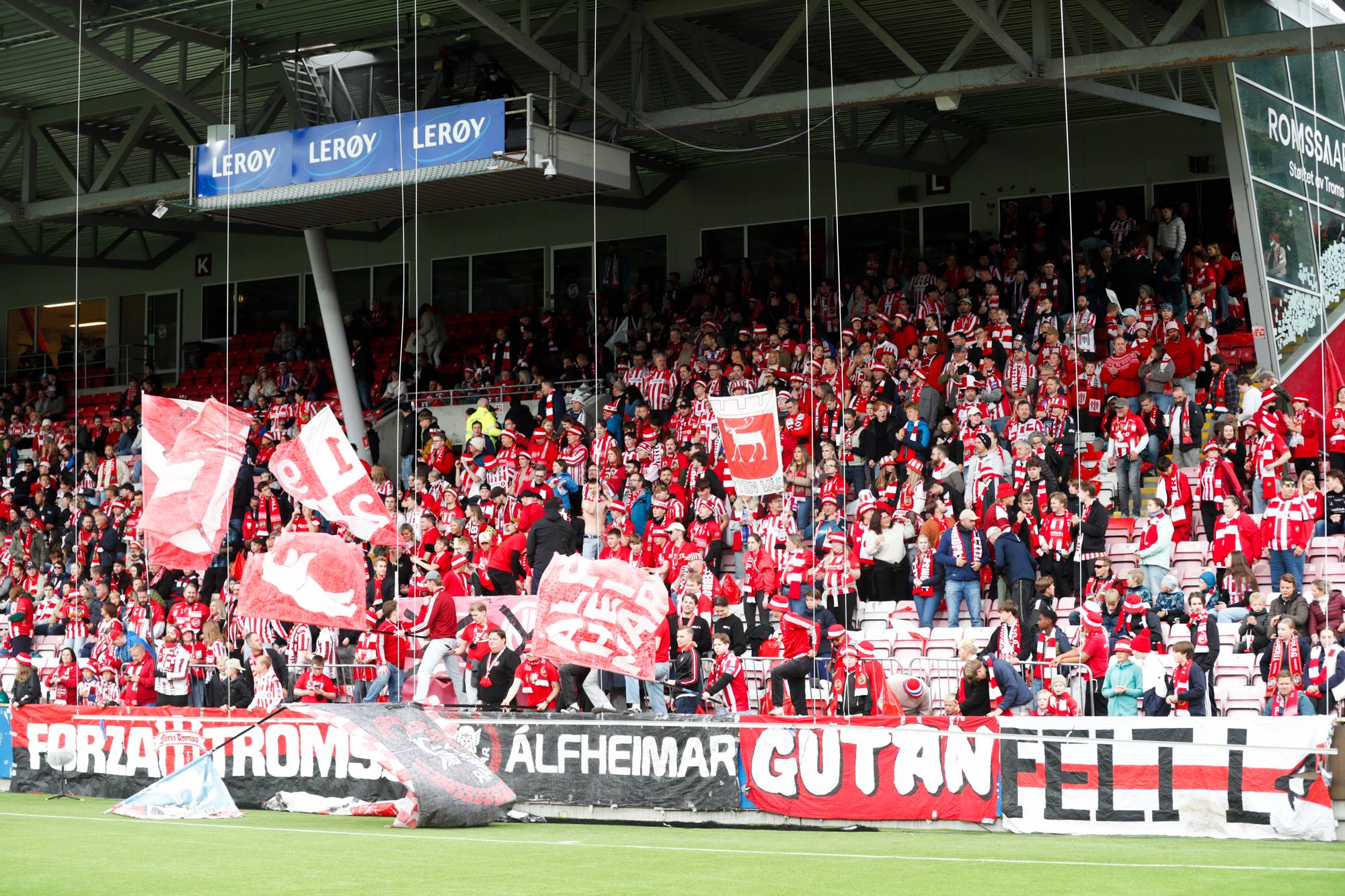 Supportere på tribunen på Alfheim stadion under en fotballkamp med flagg og bannere. (Bildebeskrivelsen er laget av en KI-tjeneste)
