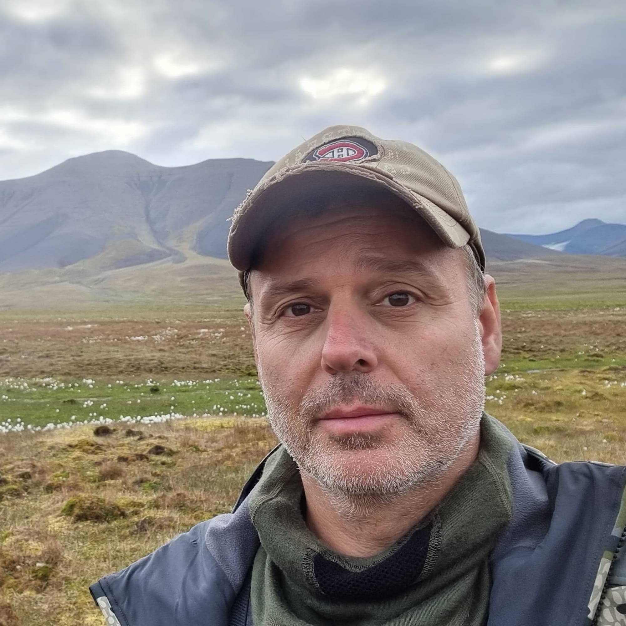 Mann med caps og turklær med fjell i bakgrunnen
