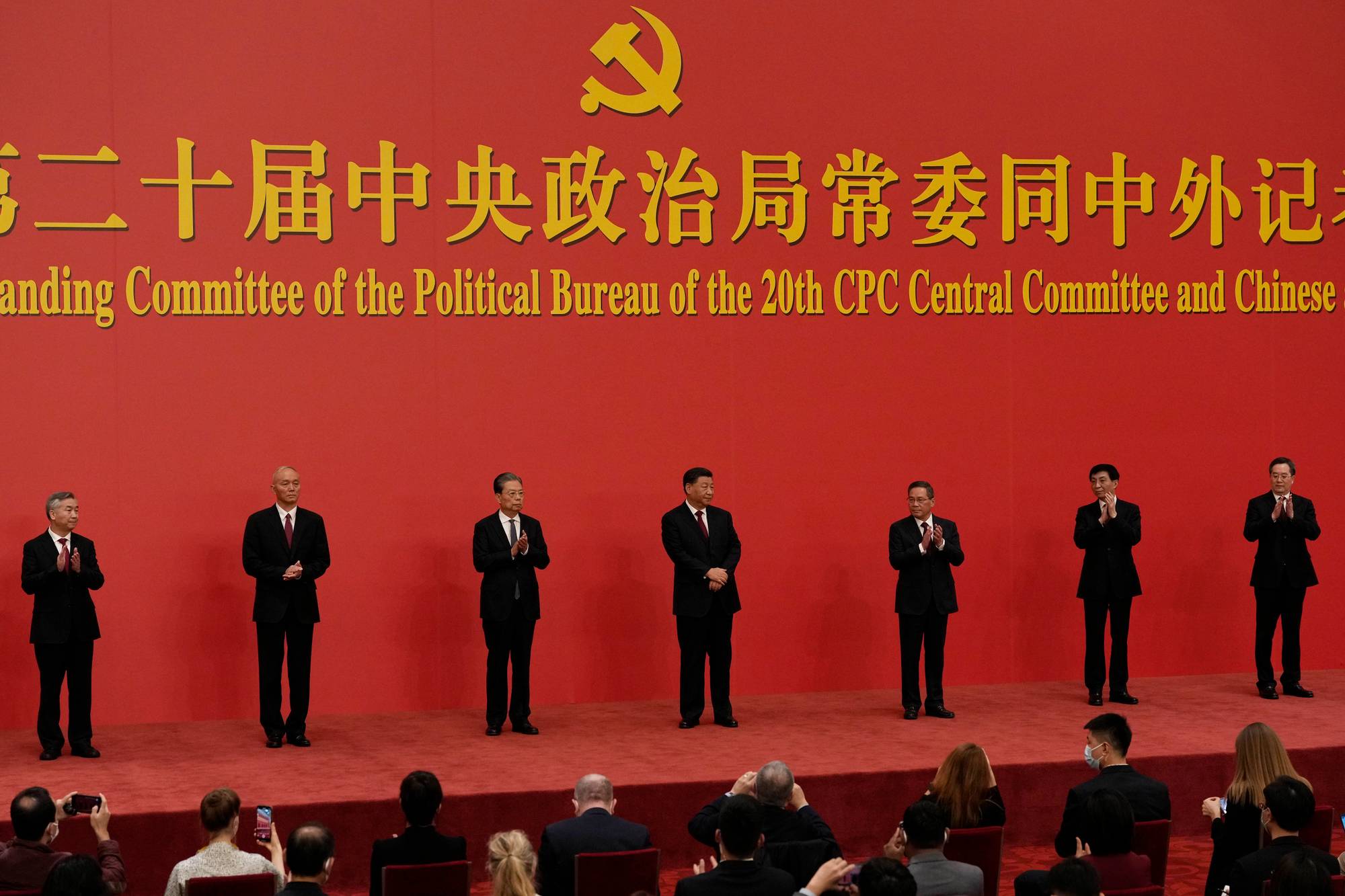 Xi Jinping og Kinas politiske ledelse på rød scene foran presse og pressekonferansebakgrunn. (Bildebeskrivelsen er laget av en KI-tjeneste)