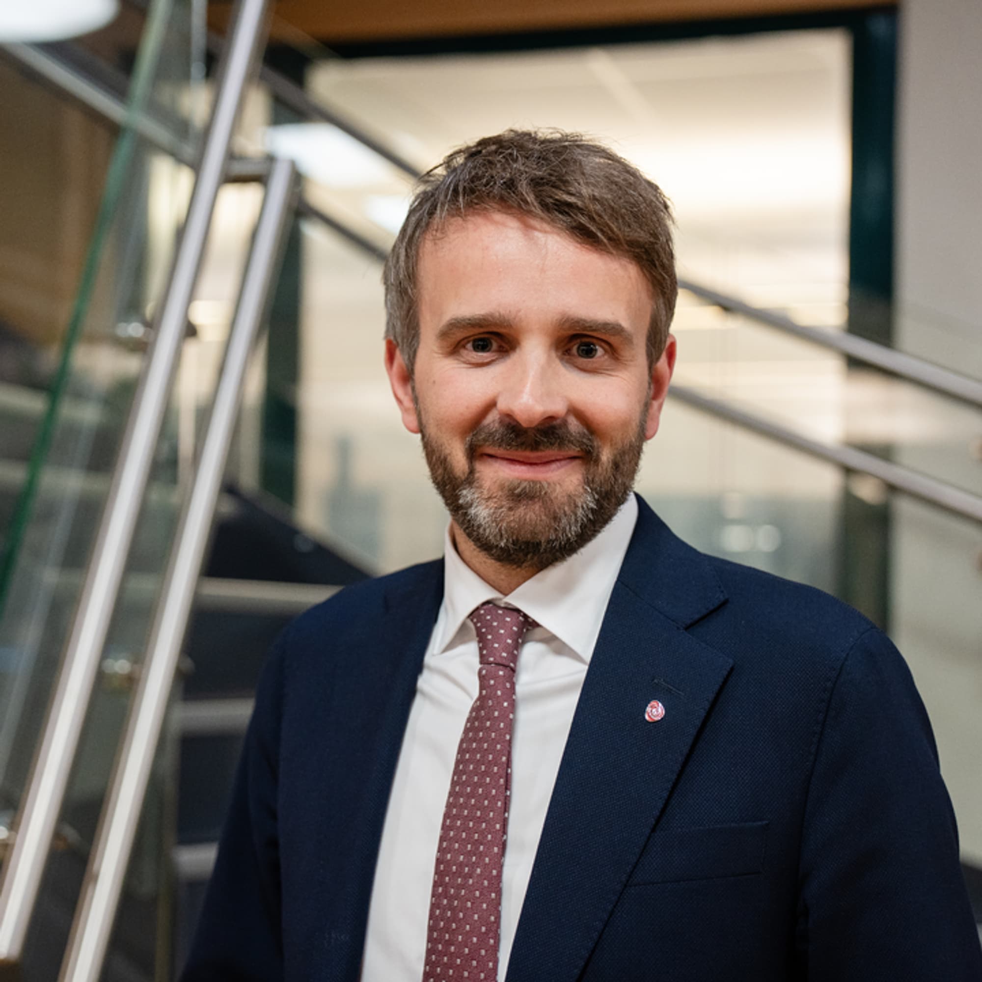  Jan Christian Vestre - nærbilde av mann i mørkeblå jakke, hvit skjorte, rødt slips, mørkt hår og skjegg