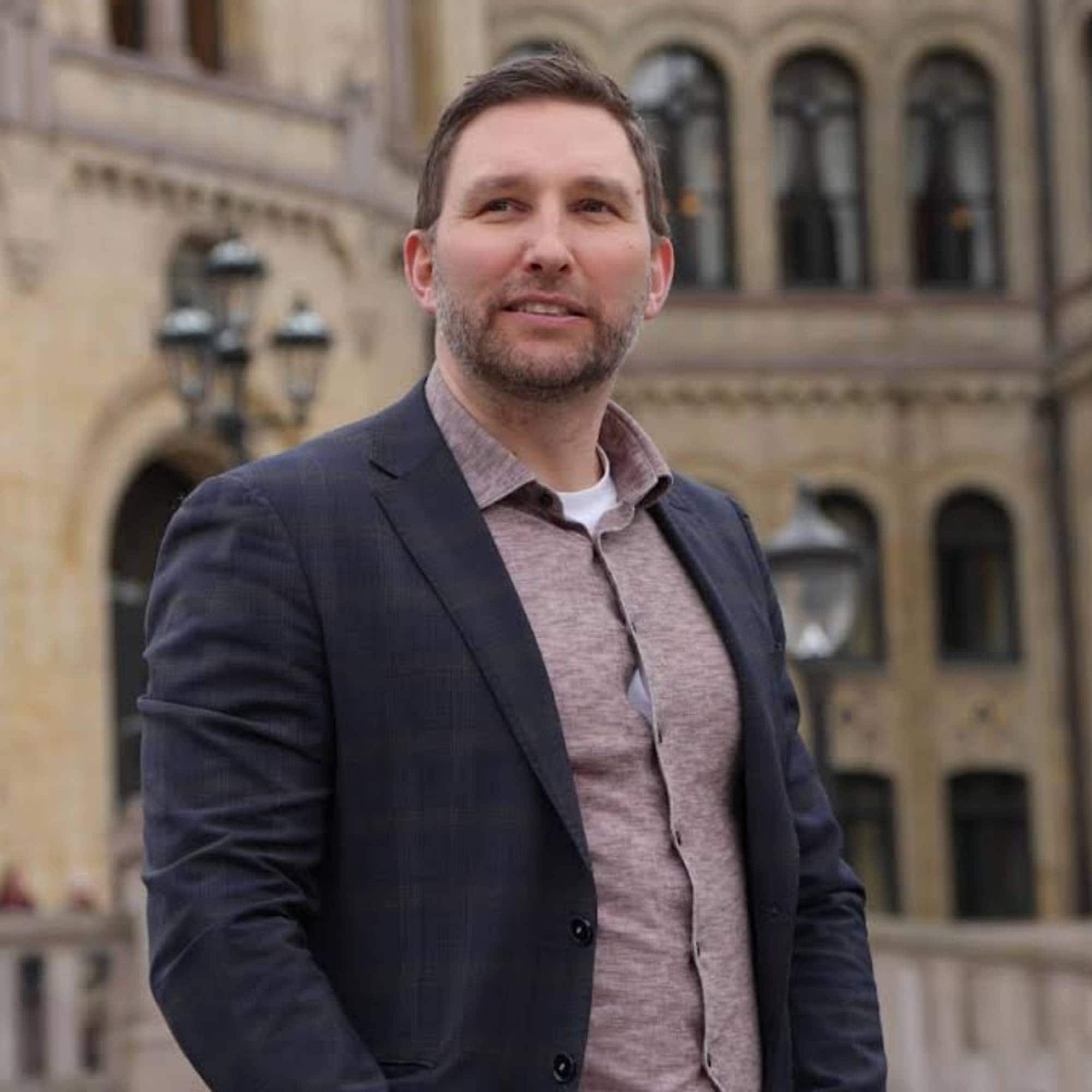 Man ser inn i kamera, Stortinget i bakgrunnen.