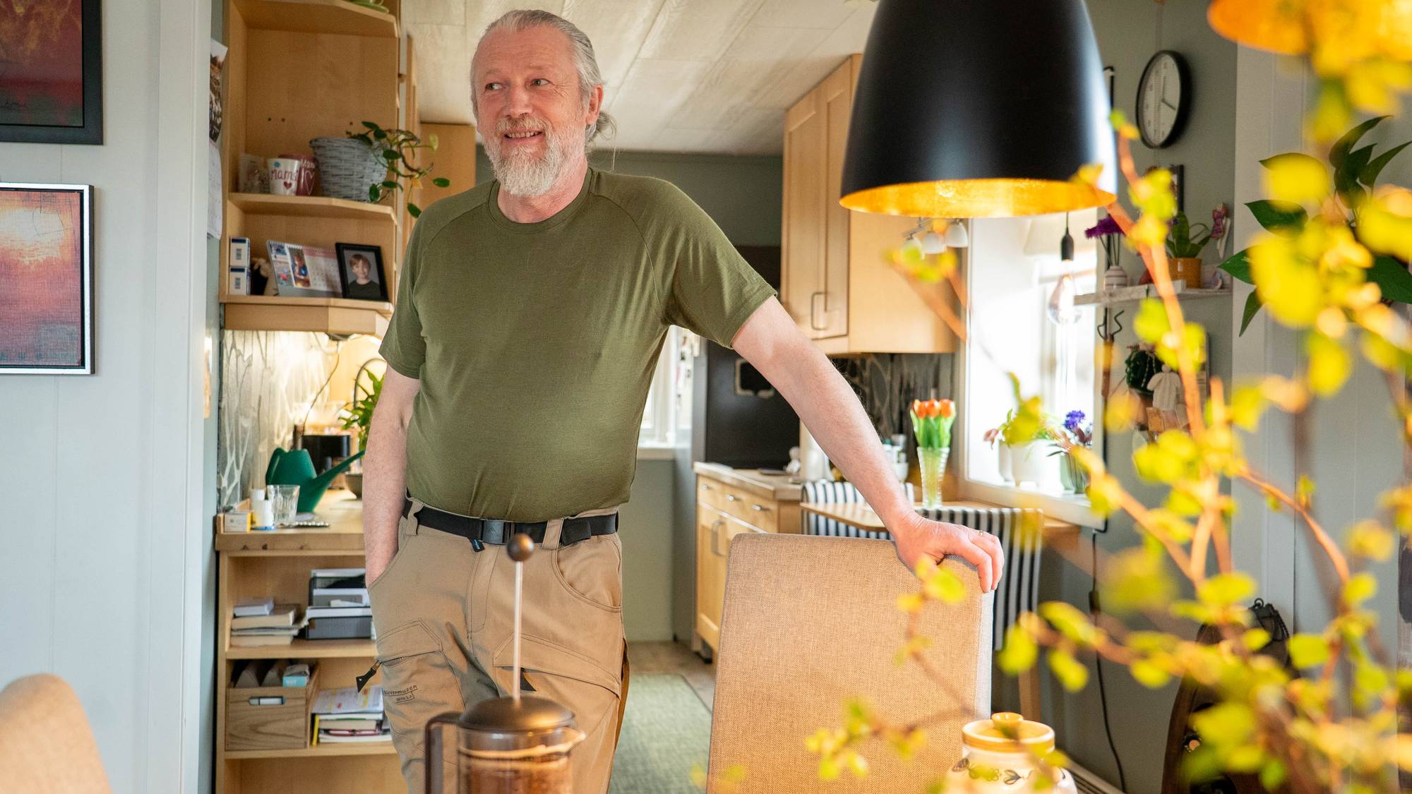 En mann med gått hår i hestehale med grønn t-skjorte
