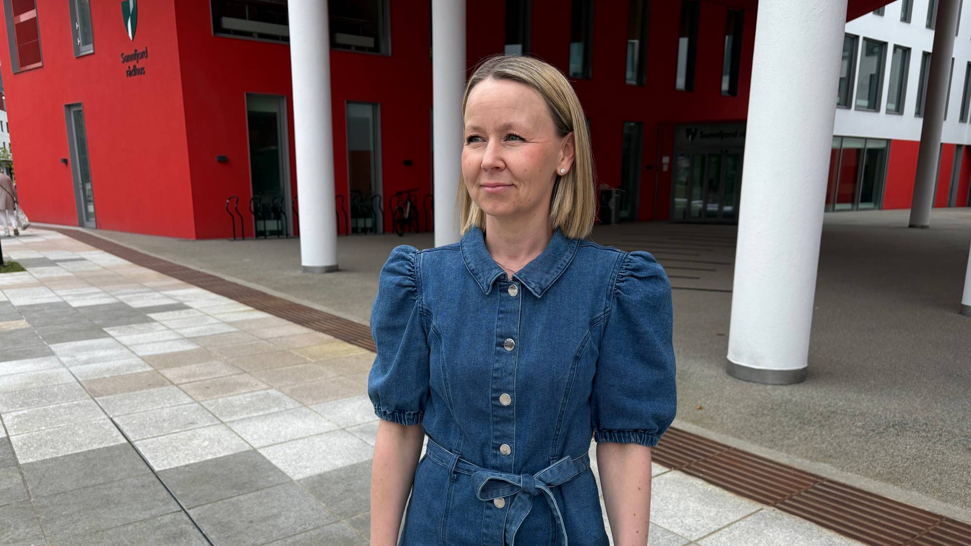 kvinne med rødt bygg i bakgrunnen