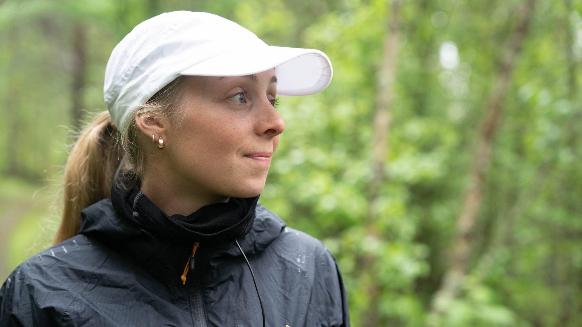 Hanna Lyrek står i skogen utenfor hundegården og smiler.