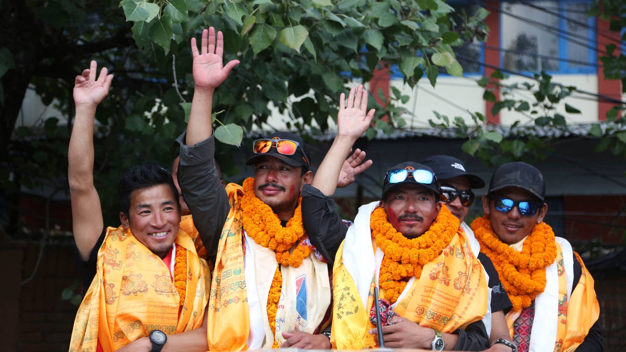 Den nepalske fjellklatreren Nirmal Purja, som ble den raskeste klatreren av verdens 14 høyeste topper, vinker til forsamlingen idet han ankommer med teamet sitt til flyplassen i Kathmandu, Nepal, onsdag 30. oktober 2019.