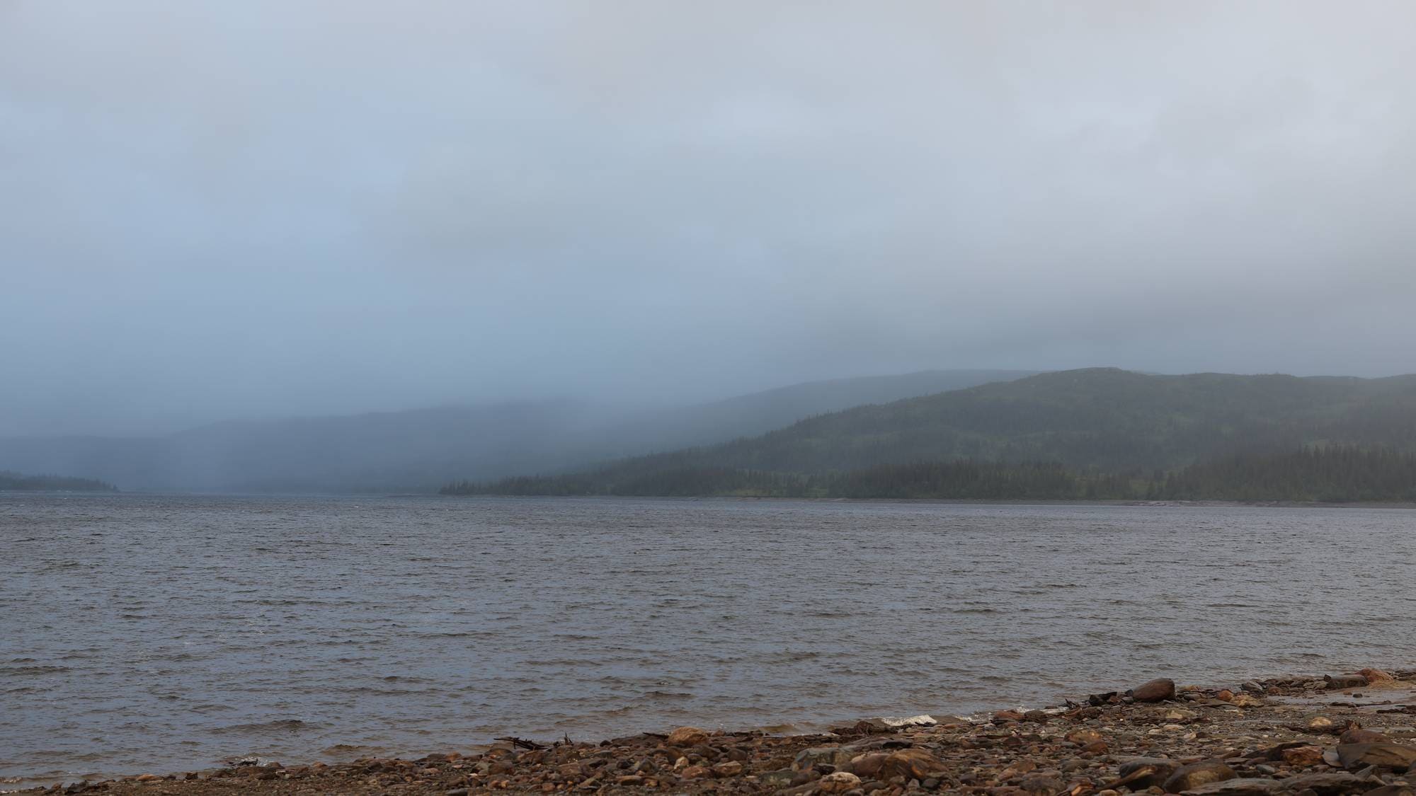 Sjø med fjell bak, dekket av tåke