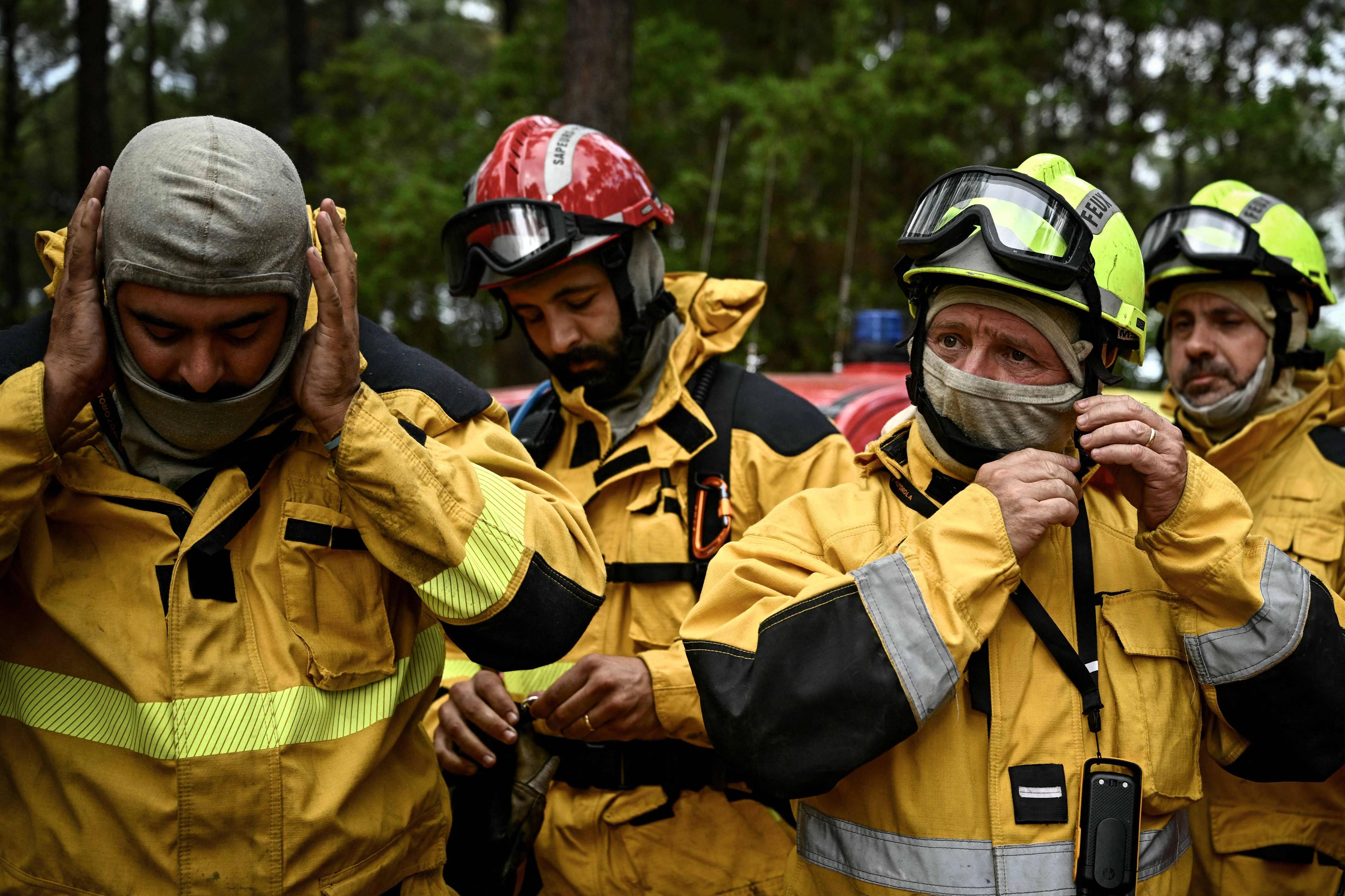 Brannkonstabler i gul uniform tar på seg beskyttelsesutstyr i et skogområde. (Bildebeskrivelsen er laget av en KI-tjeneste)