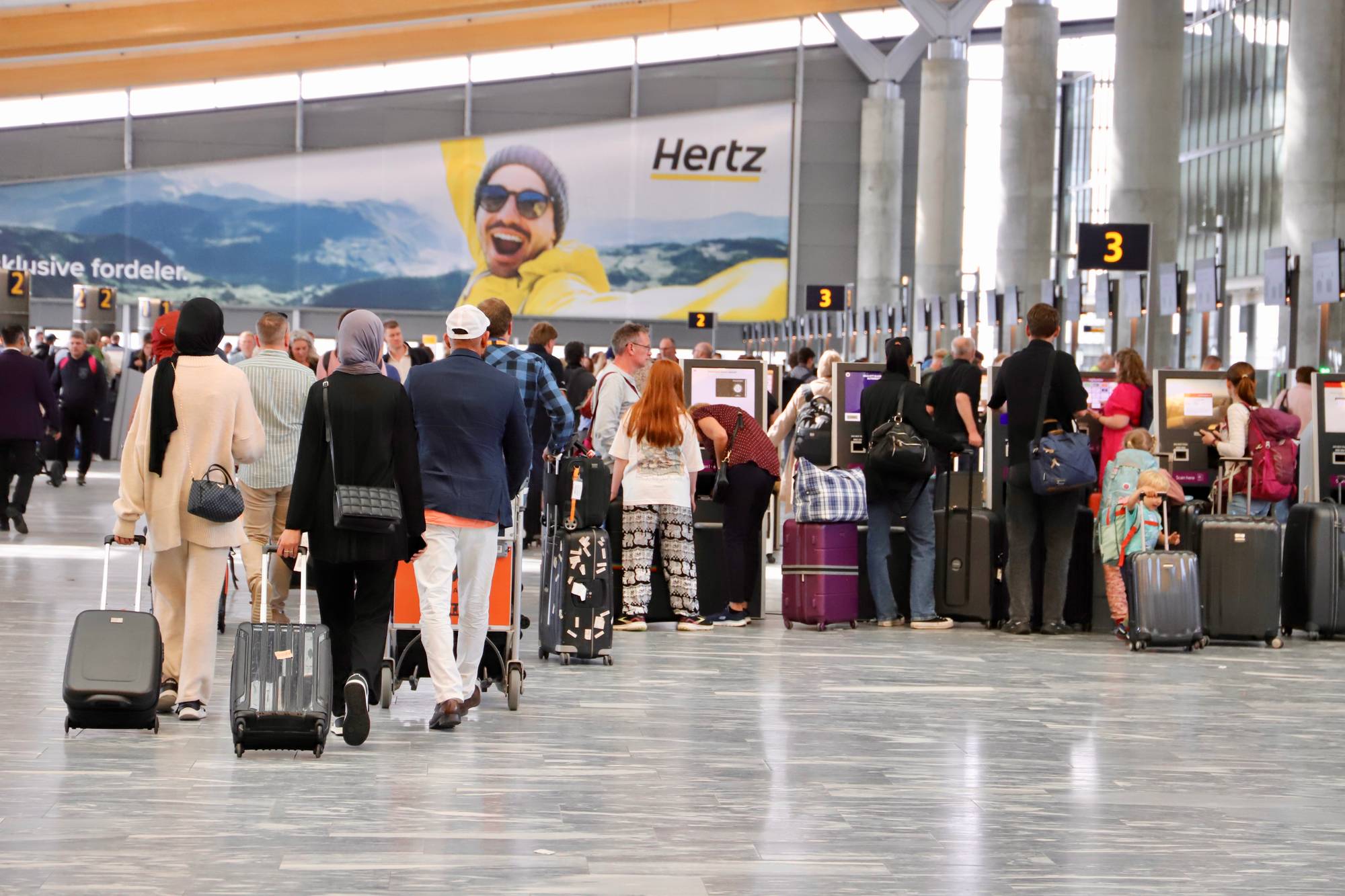 Folk i kø ved innsjekkingsskrankene i avgangshallen på Oslo lufthavn
