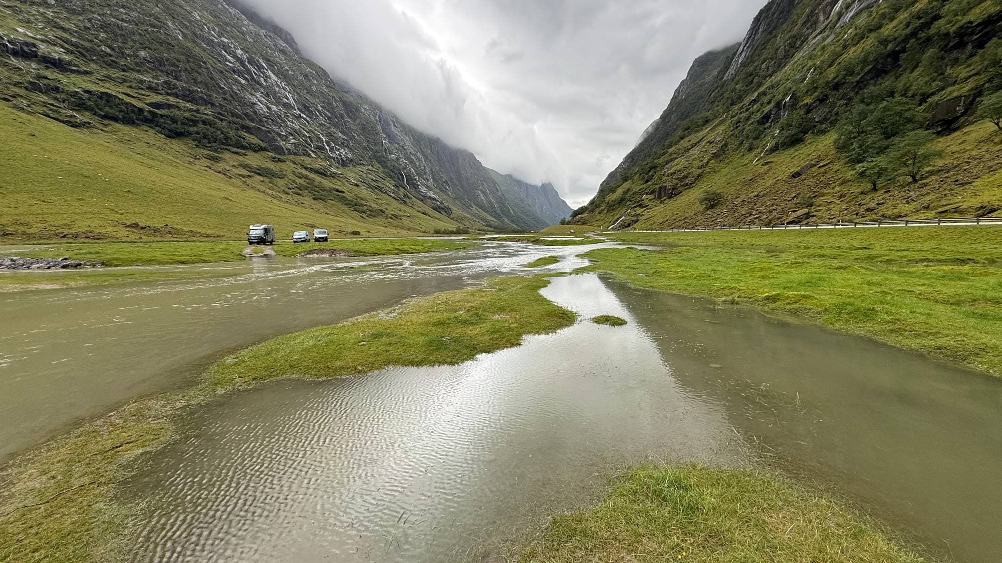 Elv i ei dal. I bakgrunnen er det campingbilar.