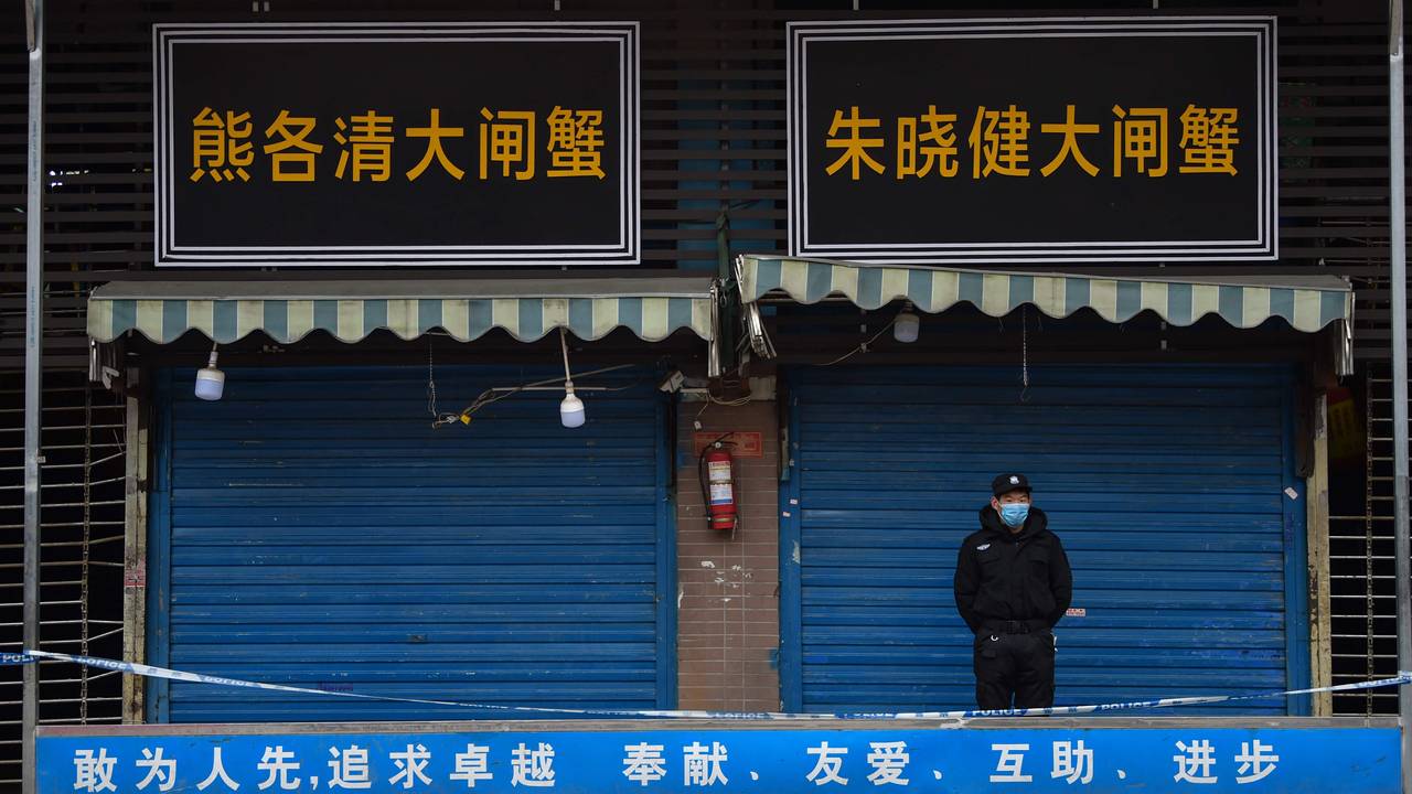 A security guard stands in front of a fish market in Wuhan, where the virus was discovered in January. 