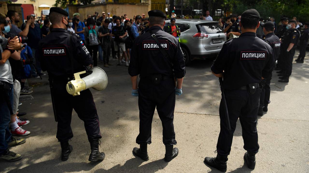 Police officers watch supporters of Ivan Safronov