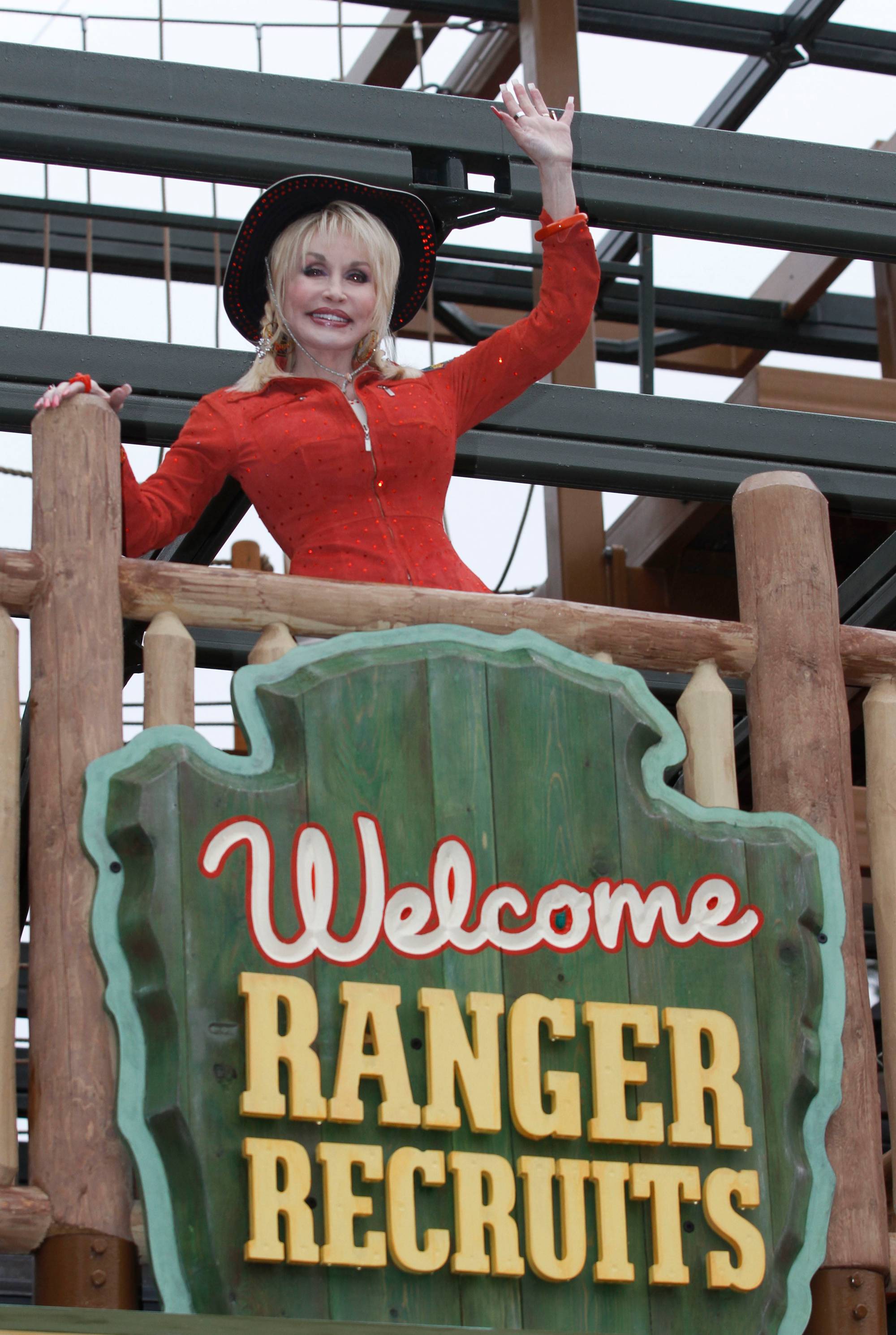 Dolly Parton vinker bak et skilt med teksten Welcome Ranger Recruits. (Bildebeskrivelsen er laget av en KI-tjeneste)